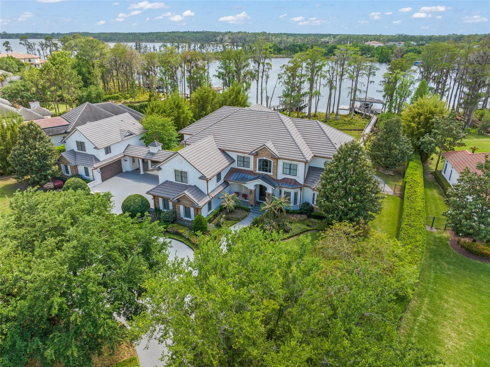 Experience elevated lakefront living in this beautifully updated estate, within the prestigious guard gated golf community of Keene’s Pointe, offering direct access to the Butler Chain of Lakes. With over $850,000 in upgrades, this home is perfectly positioned to capture breathtaking sunset views and nightly Disney fireworks from the primary suite.  This home delivers a rare combination of privacy, luxury, and lifestyle.
Thoughtfully designed for both everyday living and effortless entertaining, the residence features water views from multiple living spaces, a layout that balances open gathering areas with private retreats, and dedicated spaces for both relaxation and recreation. 
The primary suite is a true retreat, featuring a private balcony overlooking the tranquil backyard and lake. A dedicated lounge with a beverage bar, updated spa-inspired bathroom, and custom walk-in closet create a refined and relaxing escape.  Every bedroom is an ensuite, providing exceptional comfort for family and guests, while two fully remodeled junior suites showcase modern bathrooms and expanded custom closets.
On the main level, enjoy formal dining complemented by a wine cellar, while a double-sided gas fireplace connect the family and game rooms which adds warmth and ambiance. The spacious game room and media room ensure there is always something to enjoy indoors.
Step outside to your private oasis, where a resort-style pool and spa, fully equipped outdoor kitchen, covered dining area, and outdoor fireplace set the stage for year-round enjoyment. Retractable screens provide shade and comfort during the summer months, while the updated dock and boat lift make lake access effortless. A private canal connects you to Lake Tibet and the greater Butler Chain, offering the best of true lakefront living.
For extended stays or multi-generational living, the apartment above the detached garage offers a private, fully functional space complete with a kitchenette, full bath, walk-in closet, and laundry.
Positioned on a quiet cul-de-sac, this estate offers enhanced privacy along with an expansive driveway and turnaround for effortless arrivals and guest parking. The impressive five-car garage, along with a dedicated golf cart garage, provides exceptional space for collectors, storage, and embracing the Keene’s Pointe golf lifestyle.
This is more than a home—it’s a complete lifestyle experience. From lake days and sunset views to golf, dining, and the best of Central Florida just minutes away, this property delivers the elevated living today’s luxury buyer expects.