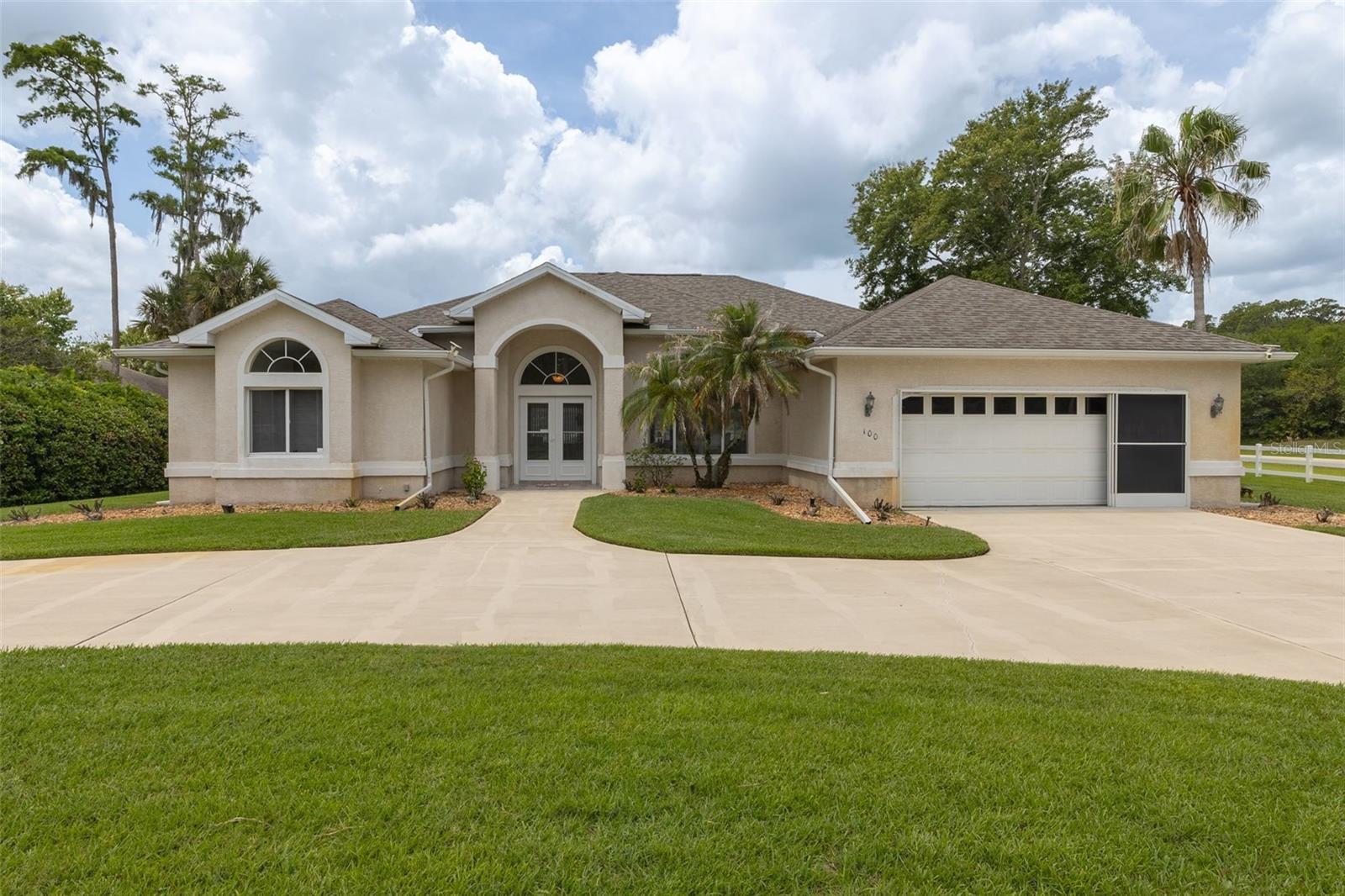 Welcome home to this beautifully maintained 3-bedroom, 2-bath residence situated on a large corner lot with impressive curb appeal, a circular driveway, lush landscaping, fruit trees, and partial white vinyl fencing for added privacy. Modern smart home features allow convenient remote control access, blending comfort with today's technology.
Step through the double-door tiled entry into a spacious living area accented by a lighted art niche and coat closet. The formal dining room is perfect for entertaining, featuring a tray ceiling and a large picture window overlooking the landscaped yard.
The heart of the home is the inviting kitchen, complete with white cabinetry, white appliances, pantry, breakfast bar, built-in desk area, tile flooring, and an adjacent casual dining area with ceiling fan. The spacious family room offers laminate flooring, transom windows, a built-in entertainment center, and abundant natural light.
Relax year-round in the Florida room surrounded by oversized windows and peaceful backyard views. Sliders from the formal living room, casual dining area and the primary suite create seamless indoor-outdoor living.
The primary retreat features laminate flooring, private access to the Florida room, dual walk-in closets, and an en-suite bath with double sinks, linen closet, garden tub, and walk-in shower. Two guest bedrooms provide flexibility for family or office space, with one featuring plush tan carpeting and the other laminate flooring.
Additional highlights include an inside laundry room, 2-car garage with epoxy floors, pedestrian door, and electric garage door opener, gutters, sprinkler system on a well, AC replaced in 2023, and roof replaced in 2022.
This home offers the perfect combination of functionality, comfort, and Florida living both inside and out.  It also offers close proximity to the Daytona International Speedway, Target, plenty of restaurants such as Panera Bread, Cracker Barrel, Houligans, Cheddars & many more along with plenty of shopping such as the Volusia Mall, the Tanger Outlets, Tomoka Towne Center & the Port Orange Pavillion.  And do not forget the World's Most Famous Beach is only minutes away.
The home currently has audio & video in all rooms & on the exterior.  All measurements are approximate & not warranted.
