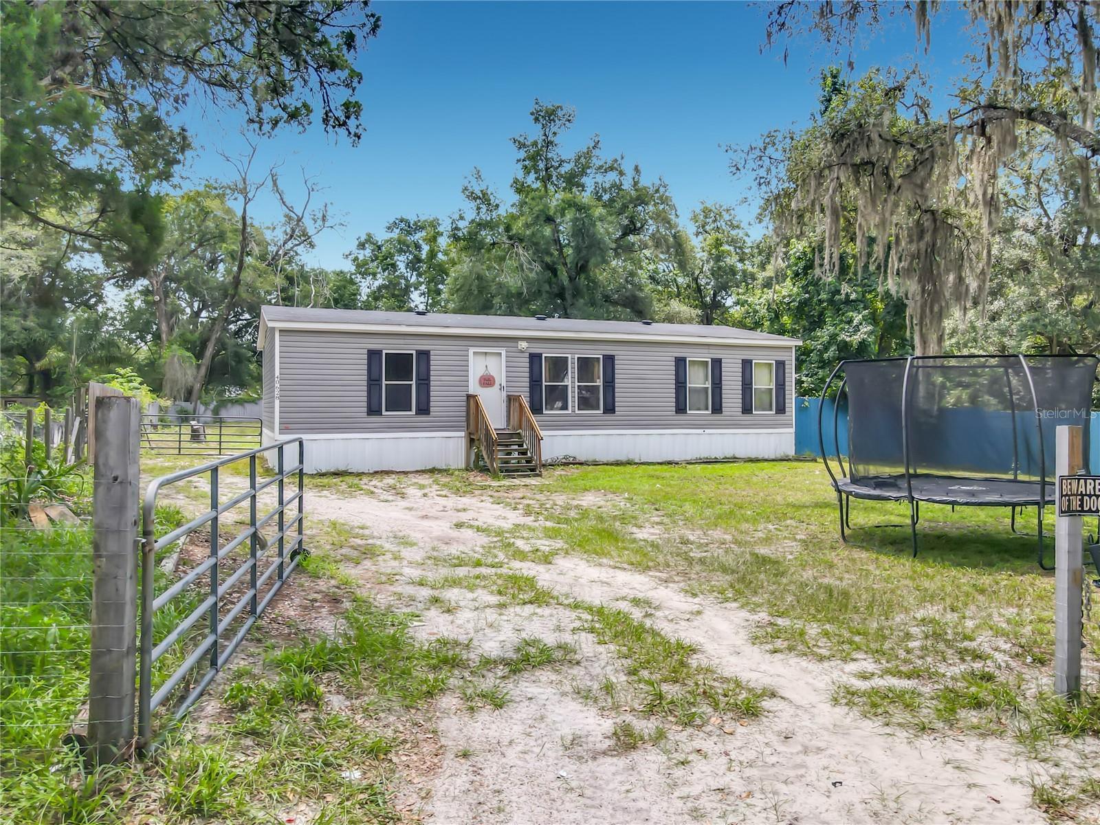 Welcome to this beautiful, move-in-ready double-wide manufactured home nestled in the peaceful community of Eustis, Florida. Offering 1,352 square feet of thoughtfully designed interior living space, this home features an open concept floor plan, a spacious living room, and dedicated dining area. The clever split-bedroom layout ensures maximum privacy, highlighting a generous primary suite complete with a walk-in closet, alongside two additional bedrooms and a second full bathroom. The functional kitchen comes fully equipped with a modern range, oven, refrigerator, and dishwasher, making meal preparation a breeze. Step outside to discover the property’s standout feature: an expansive, fully fenced backyard that offers an abundance of open space perfectly suited for storing your cars, trucks, trailers, and outdoor toys. Located in Lake County with easy access to regional thoroughfares, this turnkey property perfectly blends a quiet, country-style atmosphere with all the modern conveniences of central Florida living. Situated in a prime location for outdoor enthusiasts and commuters alike, this property offers incredible proximity to some of Central Florida’s most prized destinations. You are just a short drive—roughly 15 to 20 minutes east—from downtown DeLand, known for its award-winning, historic main street, local boutique shopping, and vibrant dining scene. Nature lovers will appreciate being right on the doorstep of the Ocala National Forest, which begins just a few miles north and offers over 380,000 acres of hiking trails, hidden natural springs, and pristine wilderness. Additionally, the historic St. Johns River is just minutes away, providing effortless access to world-class boating, fishing, and waterfront relaxation. Whether you are heading out for a day on the water, exploring the forest trails, or spending an evening in town, this home serves as the perfect base camp for the ultimate Florida lifestyle.
