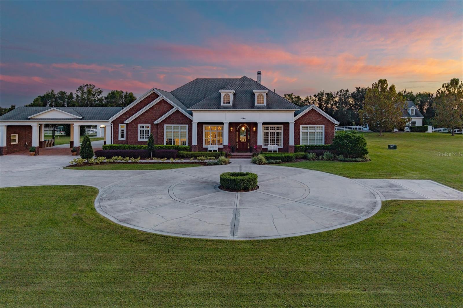 Discover the epitome of equestrian luxury with this pristine 5.85-acre estate, featuring a state-of-the-art four-stall barn, premier riding ring, and a meticulously designed custom home and guest house. Strategically in Central Florida, just minutes from major roadways and an easy location to all the major horse shows and events Florida offers. Property also backs up to an 18-hole beautiful golf course, adding to the privacy of this property.  This exceptional estate’s main residence boasts 8,261 sf of luxury living with seven bedrooms, five baths, all carefully renovated with designer selections. Gorgeous formal dining room can seat 12, ideal for those special holidays. An incredible chef’s kitchen features a bar-style center island, all opening to large gathering space, which features a gorgeous fireplace with custom-built mantle. The chef’s kitchen is home to updated stainless appliances, custom wood cabinetry, center island with sink and bar seating, granite counters, hidden pantry, double refrigerator and freezer, and generous counter space to spread out. The back of house has views from an incredible window and door bank, which allows beautiful ambient light through the house and overlooks the outdoor resort-style pool and entertaining area. This is the home your friends and family will gather in and want to stay! The home office or flex room is designed for a golf simulator, so practice your game while taking those work calls. As you go outside, an outdoor paradise awaits, where the pool takes center stage for a staycation at home with a lazy river, spa, pool cabana and firepit, and deck that wraps the pool, providing plenty of space for a large crowd. The covered lanai extends across the back and includes a fully appointed summer kitchen with room for alfresco dining space to soak in the Florida weather. Primary suite with spa-like bath, which includes dual vanities, steam station of clothing, makeup vanity, double head shower, jetted tub and built-in jewelry cabinet. Two of the seven bedrooms are upstairs with great landing area. Home has terrific storage and every detail accounted for. The equestrian amenities are designed for horse lovers and include four stables, a tack room, sliding doors on three sides, an incredible 1,800-square-foot garage with roll-up doors for ease of parking your vehicles and toys, as well as a Tesla charger. A 1,324-square-foot porte-cochere connects the main house to guest house. Guest house or in-law suite is 1,620 square feet, three bedrooms and two baths, providing privacy for all. The function of this property is designed for the serious equestrian in a serene location while being close to a city lifestyle. Other features of the unique property include whole-house generator (Generac), inside laundry organization center with pet washing area, plantation shutters, Icynene insulation, irrigation (not in pastures), crown molding and chair rail, central vacuum system, in-floor outlets, tankless water heater, garage roof 2022, upstairs air conditioner 2023, and more. This property was carefully designed with the highest quality architectural details and craftsmanship, so expect to be impressed. If the equestrian lifestyle is what you are looking for, this location and property cannot be matched. In the heart of Central Florida, it is close to attractions, airports, downtown Orlando and more. Only five minutes by golf cart to Kissimmee Bay Country Club and golf course. Inquire about a private tour.