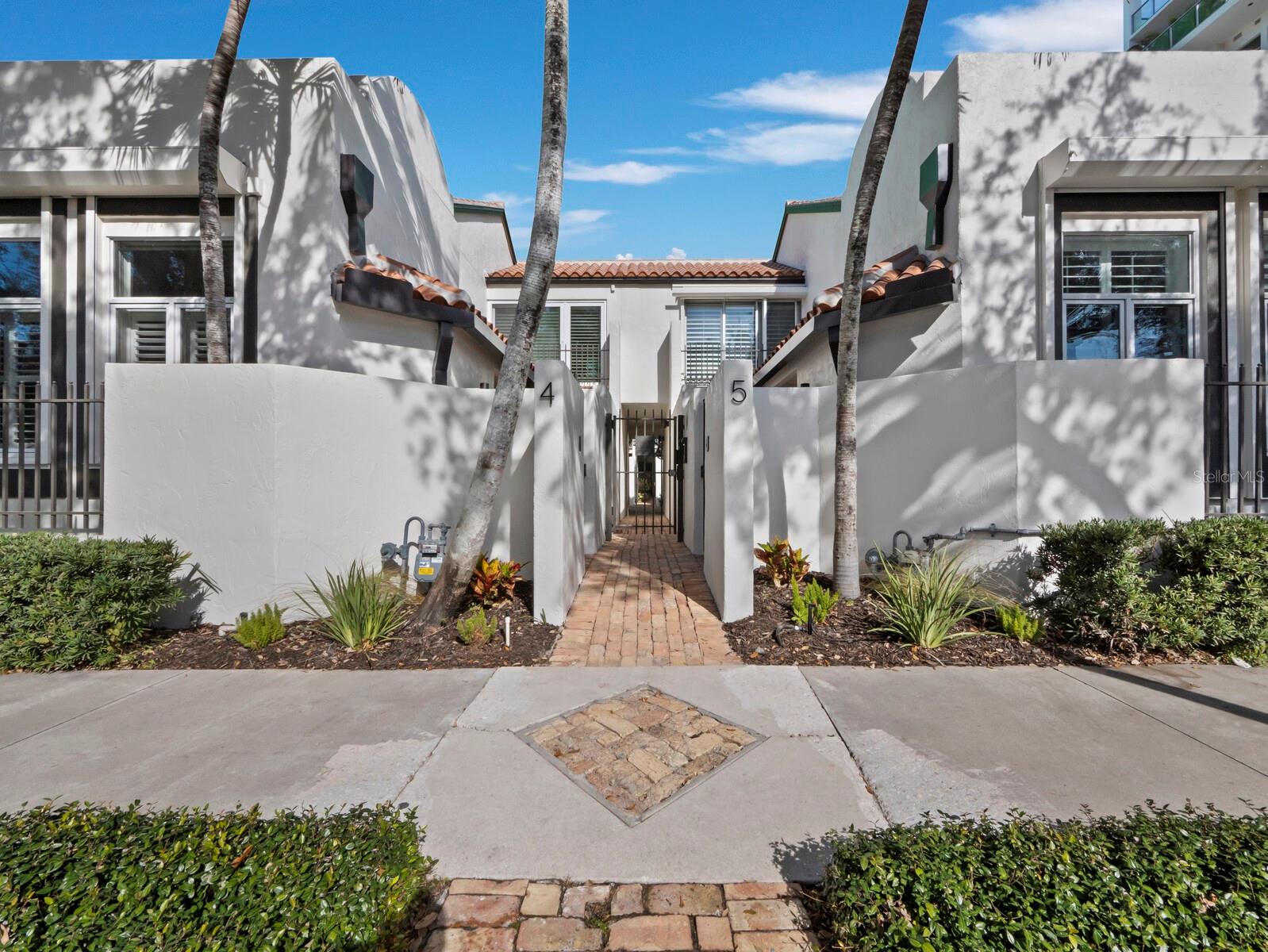 A Hidden Gem in the heart of Downtown Sarasota! Experience vibrant urban living with an old-world European style ambiance at Library Mews. This enclave is a unique intimate gated community of 11 townhome villas. The welcoming private courtyard entrance framed by an arch canopy of bougainvillea leads to the home and sets the stage for the residence’s charm. The private brick-paved courtyard leads you to your shaded indoor-outdoor patio space, an excellent place to dine or simply enjoying Sarasota’s weather. This 1,721 square foot villa features two spacious bedroom suites, two and a half baths plus a separate second-floor garden terrace, and a private garage. Upon entering the front door, the tone is set with creative architecture that provides just the right balance of a pleasing floor plan with functionally-defined living spaces. Warm hardwood floors flow throughout the kitchen, living and dining areas, complimented by soft neutral finishes such as light fixtures, crown molding, tray ceilings with LED lighting, and ceiling fans. The generous living room is highlighted by a stylish gas fireplace, high ceilings, and oversized windows with custom crown molding and a southern exposure for abundant natural light. Hurricane rated sliding glass doors seamlessly connect to the indoor and outdoor spaces. The kitchen overlooks the tranquil courtyard and features a cooking island, stunning Carrera countertops, sleek cabinets, gas cook top, and GE-pro appliances, providing style and functionality. Adjacent to the kitchen is the laundry room with a closet pantry with pull-out drawers, cabinets with countertop space, and a Koolmore washer/dryer combination. Upstairs, the spacious master bedroom boasts a vaulted ceiling and floor-to-ceiling hurricane rated sliding glass doors with cityscape views, along with a large walk-in closet and well-appointed en-suite bathroom. The second bedroom features a custom wall storage with a barndoor and includes a cozy niche area that makes a great reading or office space. For added convenience, a second stackable LG washer/dryer is located on the second level. A few steps up from the two bedrooms is the resurfaced garden terrace offering an idyllic space for relaxing while enjoying views of the city. A single-car garage, accessed from Cocoanut Avenue, is enhanced with custom cabinetry, a butcher block top and a sink. Thoughtfully designed storage is abundant throughout the home, featuring multiple closets, custom cabinetry, built-ins, and a well-equipped garage to keep everything organized and out of sight. Further upgrades include impact sliding doors and bedroom windows, hurricane impact skylight, security system, new roof (2025), new exterior paint, gutters and awnings, hurricane garage door, new tankless water heater and saltwater softener system. This delightful townhouse is situated just steps from the Sarasota Theater District, Sarasota Opera, library, world-class restaurants, Whole Foods grocery store, Marina Jack, and Main Street shopping. Come live and play in the heart of Downtown Sarasota.
