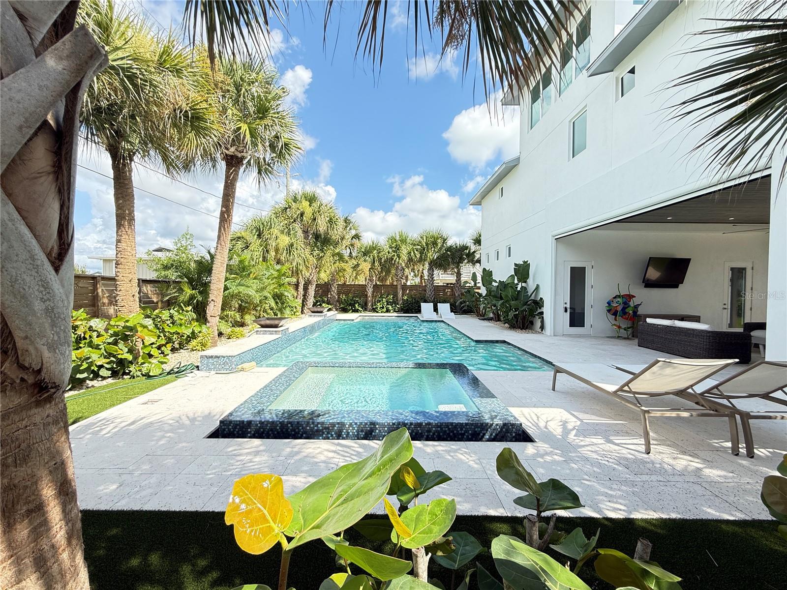 Under contract-accepting backup offers. Welcome to this stunning 2023-built oceanview coastal retreat in the desirable Silver Sands neighborhood of New Smyrna Beach. With 2 bedrooms, 3 full bathrooms, and a 4-car garage, this home blends modern comfort with relaxed beachside living. The bright open-concept main level features high tray ceiling details, crown molding and plenty of windows and balconies. The spacious living and dining areas open into a beautifully appointed gallery kitchen with white cabinetry, stainless steel appliances, a range hood, and generous storage. The primary suite offers a large walk-in closet and a stylish bathroom with a double vanity and oversized tiled shower. An upper-level loft provides flexible space for guests, a home office, or an additional lounge area while capturing beautiful ocean views. Multiple balconies and outdoor spaces invite you to enjoy the coastal setting. The private backyard is designed for entertaining, featuring a heated in-ground pool and spa, full bathroom and summer kitchen tropical landscaping, and an expansive covered outdoor living area overlooking the pool. The oversized ground-level four car garage provides exceptional space for vehicles, recreational equipment, storage, or a game area. This property is the perfect combination of a primary residence, beach getaway, or investment opportunity. It is located within 3 homes to the beach walk over and local dining.