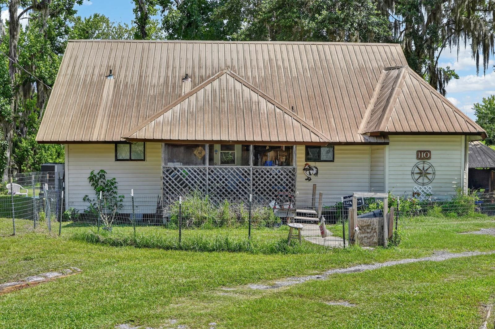 Riverside-adjacent home on over half an acre in the River Park West subdivision in Fruitland, near Crescent City. A fence encloses the home itself, while a second fence surrounds the chicken coop, ideal for anyone looking to bring a bit of homesteading to the property. The property features a double carport, a wood-burning fireplace, a large bay window, and cypress trim throughout with a metal roof overhead. Large shade trees surround the home, while an optional HOA with access to private boat ramp offers direct water access, with dock rental also available. With its generous lot size, dual fencing, and flexible outdoor space, this property offers room to spread out in River Park West