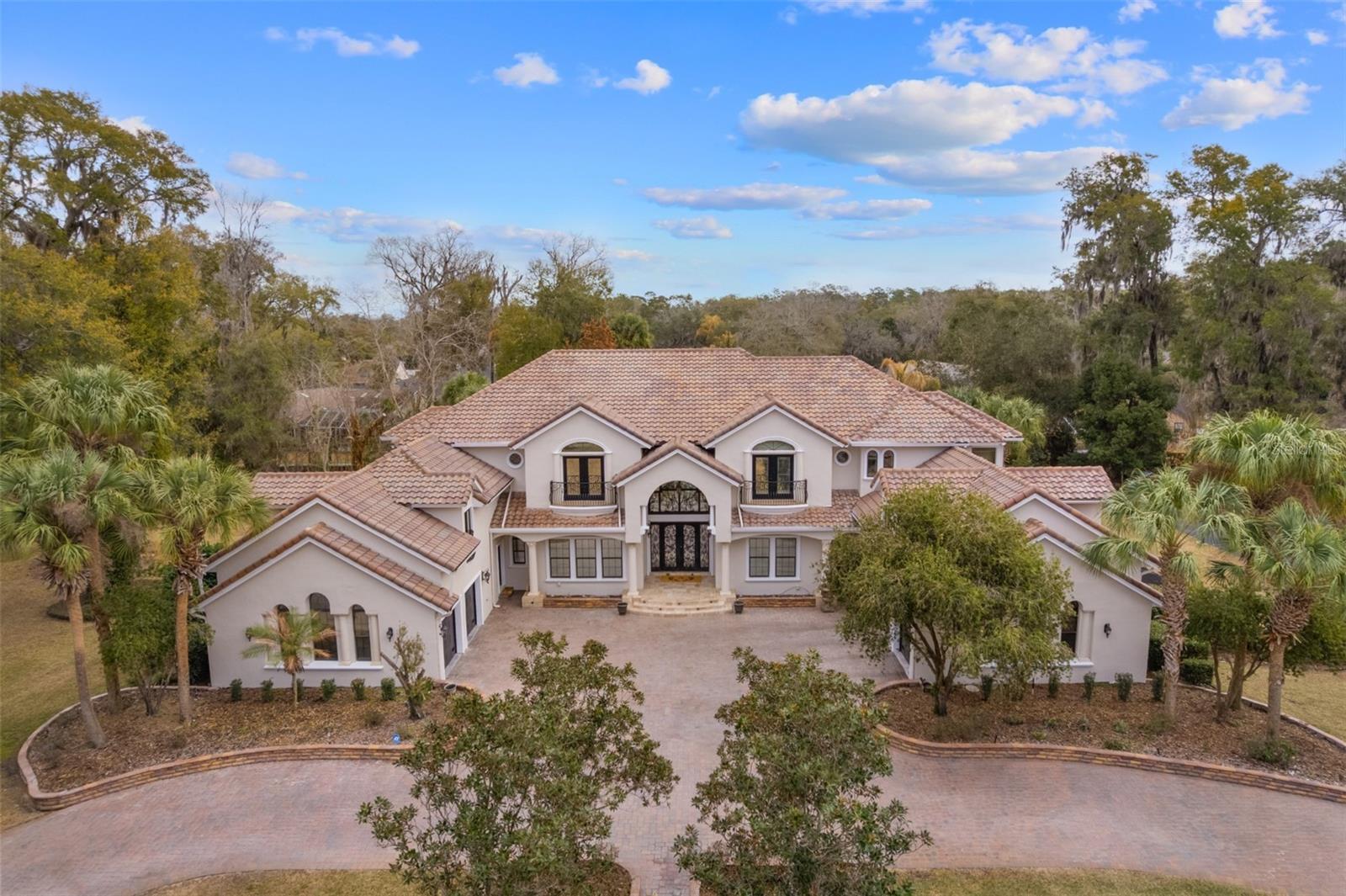 Come discover this magnificent 7,240 square foot two-story Estate Home on a double lot in the prestigious and highly sought after neighborhood of South Point. Everything in this home has been exquisitely curated to the highest standards. Upon entry you are greeted with a massive living room with soaring 24-foot ceiling bringing in tons of natural light. You will also be captivated by beautiful hand-painted murals, and delicately faux-finished walls; everything in this home has been thoughtfully crafted with excellence and elegance in mind. This home is close to everything you could want, just minutes to Downtown Ocala for shopping, dining, or other amenities, and just a short drive out to the World Equestrian Center. This gorgeous home sits on a double lot and boasts seven ensuite bedrooms as well as a full pool bath and an added powder bath. Marble and travertine flooring throughout. A generously sized kitchen with ample storage. The large family room boasts a gorgeous floor to ceiling fireplace. This home also comes with an exceptionally large office and a beautifully appointed movie theater. There is also a wet bar, wine fridge, and wine storage. This home comes with a 4-car garage. Outside you are met with a covered porch that spans the length of the home, an oversized and screened vanishing-edge pool, with hot tub, and a fully equipped outdoor kitchen. A half-court basketball court sits to the side and there are solar panels for heating the pool. Upstairs you enter a truly grand master bedroom with two large walk-in closets and a large well-appointed master bathroom. The master bedroom opens to a Verandah overlooking the pool and spa. In addition, there are six other generously sized bedrooms, all with walk-in closets and private bathrooms. There is also an added flex space that can be used as a play area, lounge or a music room overlooking the family room. In addition, there is a full gym worth of equipment that conveys with the home. This home was built with family in mind, and you and yours will be able to enjoy it for years to come.