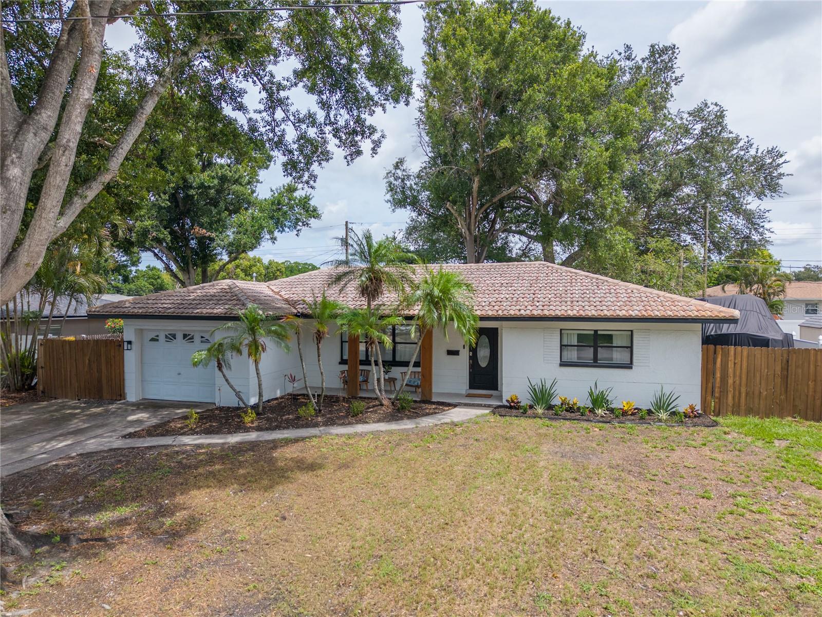 MOVE-IN READY 2 Bed, 1 Bath BLOCK home with an oversized 1-car garage. Tons of natural light, a sightline from the front door to your tropical backyard and an open concept! Features a flexible BONUS ROOM—ideal as a home office, playroom, or easy 3rd bedroom. Extensive 2022 updates include new floors, fresh paint, and a renovated kitchen with marble countertops, updated bathroom, new screened porch and more! Enjoy bug-free Florida evenings on your screened-in outdoor living space, overlooking the private, turfed backyard. Perfect your short game on the private putting green or gather around the firepit area. Ample storage provided by a huge 20-ft shed. Dedicated side-yard parking for your boat, RV, or other toys. Peace of mind with Flood Zone X and Non-Evacuation Zone status. Unbeatable location: just 15 minutes to both Downtown St. Pete and the beaches. Walkable to Publix. Nothing left to do but MOVE IN!