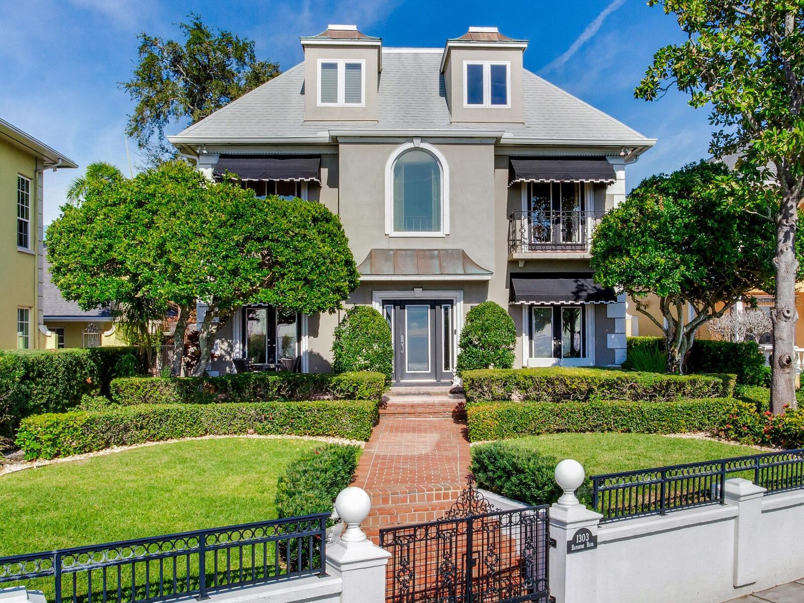 Don’t miss this rare opportunity to own this breathtaking 4-bedroom 3.5 bath timeless Bayshore Boulevard home in the most coveted neighborhood of Hyde Park Historic District. With awe-inspiring unobstructed water views on Tampa’s most prestigious walkway, this property is a must-see. The home has been thoughtfully designed and updated to ensure both traditional comfort and classic elegance.
The minute you enter the grand foyer entry, complete with a 3-story ceiling, wooden spiral staircase, arched doorways and plenty of natural light, you’ll feel right at home. The living room comes complete with wood-paneled moldings, an exquisite seating area with built-in book
cases, a wood-burning fireplace and hard-wood floors. There is also a formal dining room. The beautifully updated all-white gourmet “chef’s kitchen” features Carrara marble countertops and backsplash, a custom refrigerator and Thermador stove as well as a built-in microwave. The gorgeous center island is large enough to entertain a bevy of guests. There are 3 full large-sized bedrooms and 2 baths on the second floor. The private master suite on the third floor is complete with a luxury bath and spacious walk-in closet. Outside, entertain right in your private gated red-brick courtyard–perfect for year-round outdoor parties. Dine al fresco before walking out to watch the unmatched Bayshore sunsets right from your front yard. Additional features of the home include: a 2-car garage, 3 AC units, a built-in generator for the entire residence, as well as an alarm and irrigation system. This property is close to America’s best beaches, Tampa International Airport and walking distance to some of South Tampa’s best high-end shopping and restaurants. Named as the No. 1 best place to live in the Sunshine State by Forbes, Tampa’s prime location blends sophisticated architecture with breathtaking vistas. Don't pass up the opportunity to own this home that perfectly embodies the essence of luxury living in Florida.