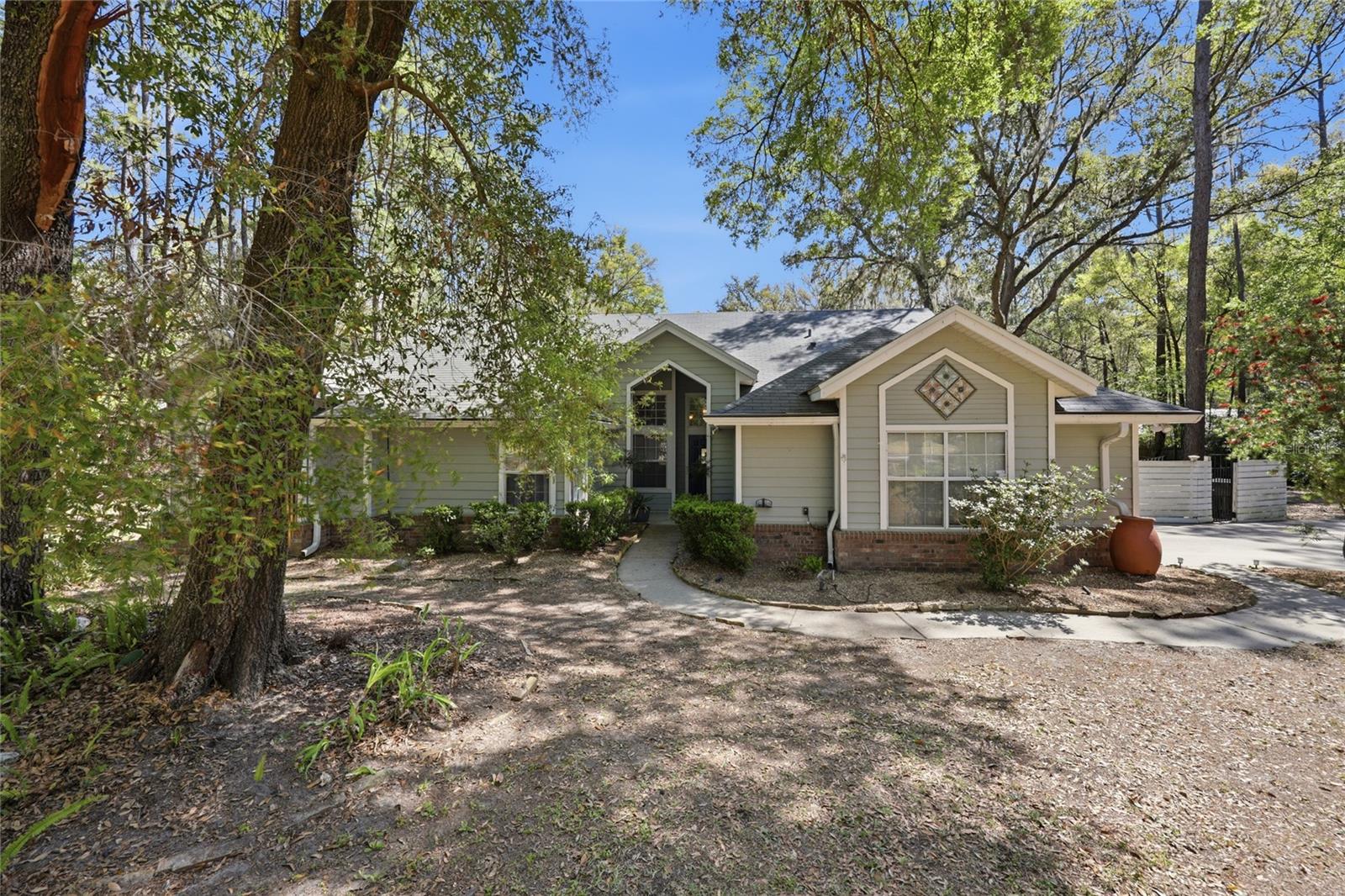 Tucked away on 2.54 private acres in a highly sought-after area of Alachua, this beautifully maintained 4-bedroom, 2.5-bath home offers the perfect blend of peaceful country living and everyday convenience—with NO HOA.
Step inside to discover a thoughtfully designed layout featuring vaulted ceilings, a spacious open-concept kitchen, and both a separate living and family room, ideal for entertaining or relaxing. The home is upgraded with new waterproof lifetime flooring, insulated windows, and stainless steel appliances, creating a modern and comfortable living space. A new Maytag front-load washer and inside laundry room with sink add even more convenience.
The split floor plan provides privacy, with a generous primary suite on its own side of the home, complete with a luxurious en-suite bath featuring a garden tub and separate shower.
Outside, you’ll fall in love with the fully fenced, park-like backyard shaded by gorgeous live oaks and dotted with your own producing ruby red grapefruit, orange, and lemon trees. Enjoy peaceful evenings on the porch swing, watching lightning bugs and local wildlife.
This property is packed with practical upgrades, including a whole-house generator, water filtration and purification systems, gutter guards, and a roof less than 10 years old. For hobbyists or extra storage, there’s both a 2-car attached garage and an impressive 3-bay detached garage.
Located outside city limits yet just minutes from everything, you’re only: 10 minutes to Jonesville, Newberry, and Alachua.  15 minutes to Gainesville.  Within 10 minutes of four Publix shopping centers
Additional features include Clay Electric utilities, Thursday garbage and recycling pickup, fiber optics, and Cox digital cable/internet availability.
If you’ve been searching for space, privacy, and convenience all in one—this exceptional property delivers it all. Schedule your private showing today and experience the charm for yourself!
*Some pictures have been virtually staged.