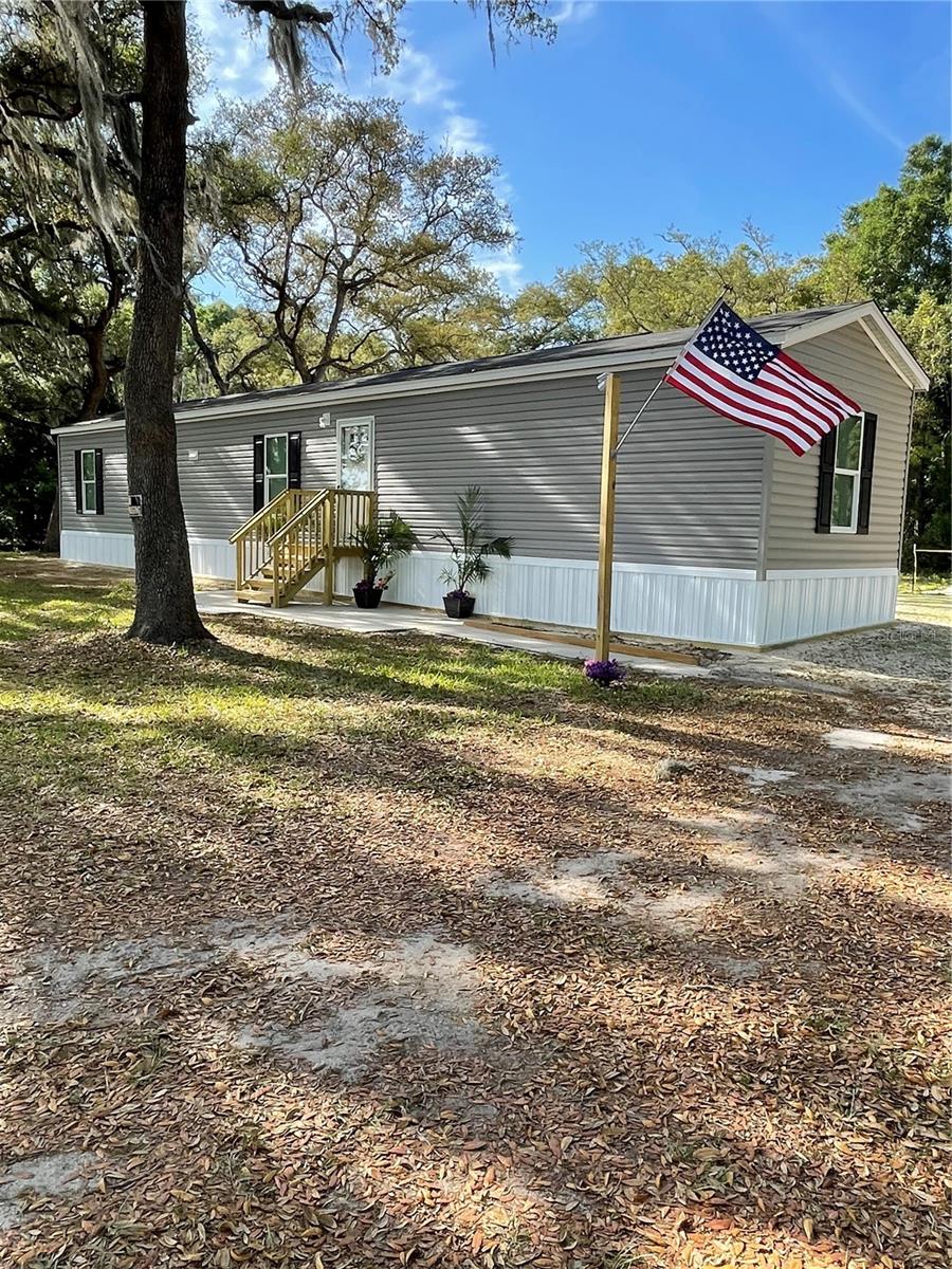 BRAND NEW 2026 single-wide mobile home on 1.40 mature acres.  This adorable 3-bedroom, 2-bath home is on a paved road and only 6 miles from Chiefland, where you have Walmart, Aldi, Tractor Supply, and many restaurants, etc.  There is a new well, new septic system, new 200 amp meter pole, and the backyard has been fully seeded (now grown in).  There is plenty of room on this fully-fenced, huge lot for a pool, a workshop, a garden, or a small barnyard.  There are huge shady oak trees, and the backyard has a useful, large concrete slab.