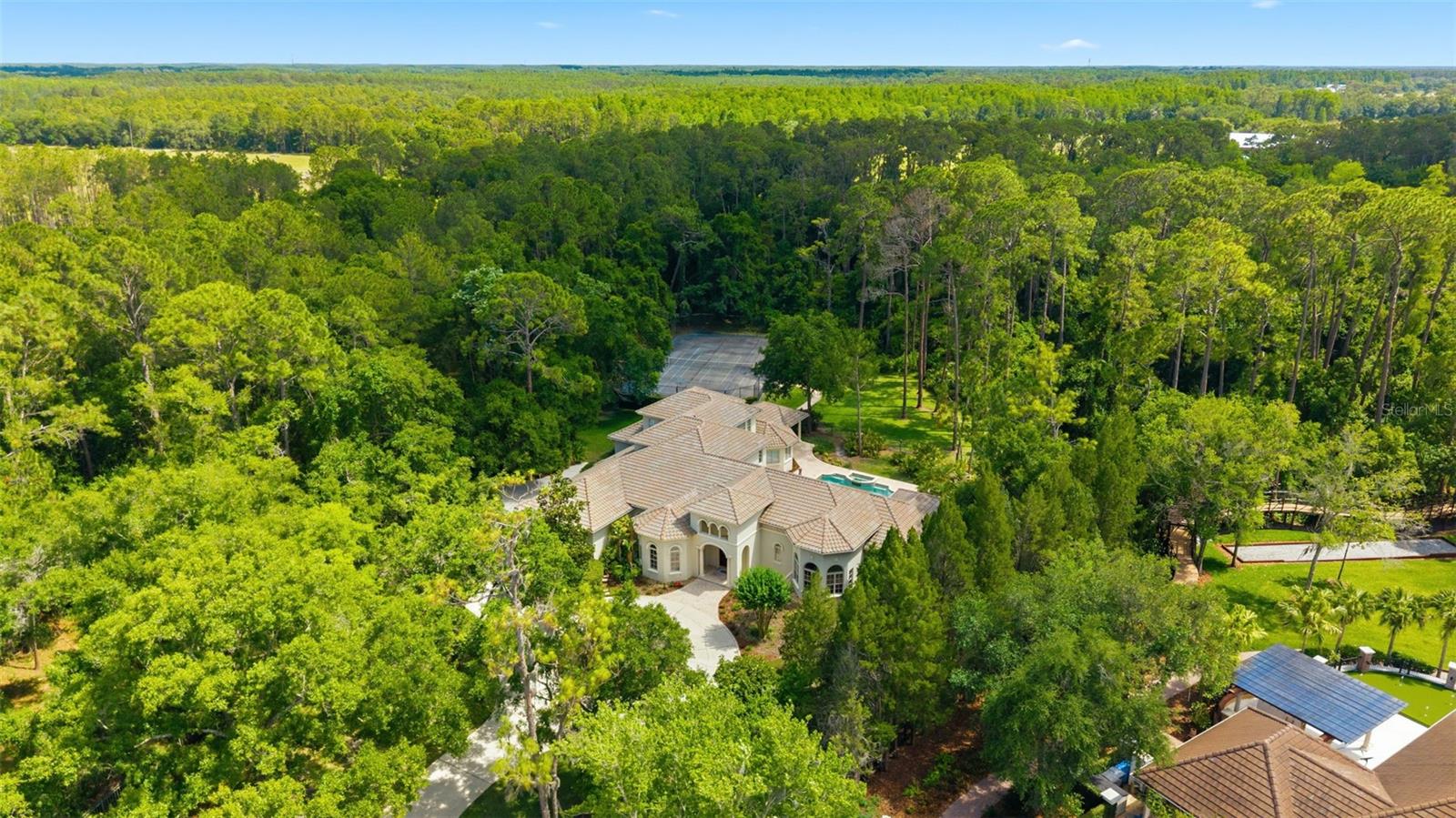 One or more photo(s) has been virtually staged. Your private santuary awaits in Stillwater.  Quick Highlights: 
 • Located within the exclusive 24-hour guard-gated community of Stillwater featuring only 48 estate homesites across 114+ acres of conservation and lakes
 • Rare 3.75-acre homesite with breathtaking conservation views, exceptional privacy, and resort-style outdoor living
 • Custom-built Jay Fechtel estate offering 5,696 SF, 5 bedrooms, 4 full baths, 3 half baths, and ALL bedrooms conveniently located on the first floor
• Option to add with an in-law suite for multi-generational living
• Private recreational amenities include a heated saltwater pool and spa, tennis/pickleball/basketball court and expansive travertine lanai with outdoor kitchen
• Chef’s kitchen equipped with Wolf double ovens, SubZero refrigerator/freezer, Bosch dishwasher, large center island, and elegant butler’s pantry designed for seamless entertaining
• 2026 Two new air conditioning systems ready for the FL Heat! 

Surrounded by breathtaking conservation views, mature landscaping, and frequent wildlife sightings, the property delivers serene estate living without sacrificing convenience. Designed for both luxury and recreation, the estate features a private tennis/pickleball court and basketball hoop adjacent to the heated saltwater pool and spa — an amenity package rarely found in residential real estate.
Spanning 5,696 square feet, the residence offers 5 bedrooms, 4 full baths, 3 half baths, and a 3.5-car side-entry garage.  Plus, a dedicated private office, bonus room and exercise room .Thoughtfully designed for today’s evolving lifestyles and multigenerational living, all five bedrooms are located on the first floor, providing exceptional comfort and functionality. Upstairs features an expansive bonus room, wet bar with refrigerator, private exercise room or secondary office, and extensive storage.
The chef-caliber kitchen is designed for entertaining and daily living, featuring Wolf double ovens, a 5-burner gas cooktop with custom hood and pot filler, SubZero refrigerator and freezer, Bosch dishwasher, large center island, and adjoining café-style dining area. A beautifully appointed butler’s pantry with glass-paned cabinetry connects the kitchen and formal dining room.

The open-concept floor plan is anchored by a dramatic family room with soaring 20-foot ceilings, hardwood floors, and expansive views of the outdoor living areas and conservation beyond. The living room features a gas fireplace, 15-foot ceilings, travertine flooring, custom ceiling details, and stunning pool views. 

The luxurious primary suite offers direct lanai access and a spa-inspired bath with dual granite vanities, custom cabinetry, soaking tub, and walk-in shower with dual shower heads. The custom walk-in closet includes built-in dressers and shoe storage. Oversized secondary bedrooms feature hardwood flooring, granite countertops, and custom closets. Two bedrooms share a Jack-and-Jill bath, while the remaining secondary bedrooms feature en suite baths.

Outdoor living rivals a private resort with an expansive travertine lanai, heated saltwater pool and spa, and a fully equipped outdoor kitchen with built-in gas grill, sink, and refrigerator beneath generous covered patios. 

Enjoy tranquil estate living just minutes from A-Rated Steinbrenner district,  the Veterans Expressway, Upper Tampa Bay Trail, premier hospitals, professional sports venues, and Tampa International Airport.