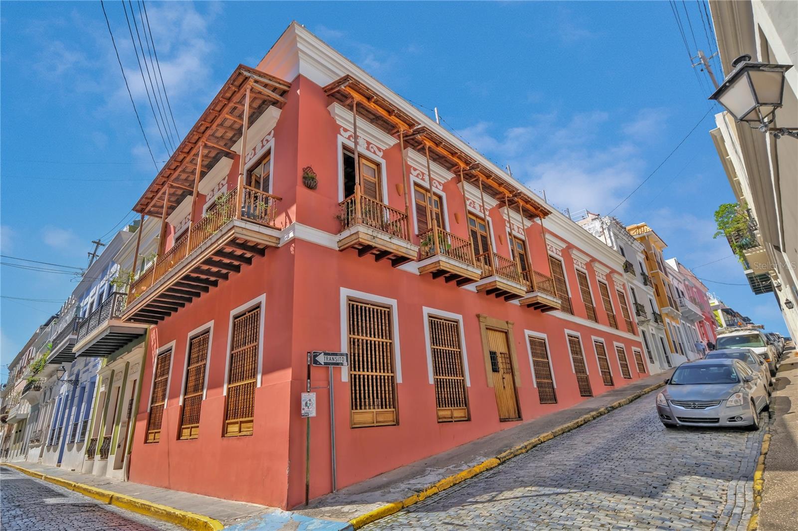 Impeccably Restored Historic Home with Enormous Rooftop Deck and Two Kitchens! Located on the corner of Sol St and C. de San Justo, this 6BR/2BA residence captures the imagination with whimsical terraces, beautiful window spindles, and a vibrant exterior. Owned in the 1800s by the then-wealthiest sugar baron, José Ramon Fernández, the property has continued to enjoy the presence of Old San Juan’s notable residents, including a former governor (circa 1900s). Thoughtful consideration was made while restoring this historic gem. All of the original bricks were saved, ironwood beams preserved, and frescos given new life. Showing like a dream, the property offers versatility for investors and/or multigenerational households. Boasting two floors, each level may be used independently or as a singular household. This remarkable 8,600 sqft estate offers 5,700 sqft of meticulously designed indoor living space, complemented by 2,900 sqft of outdoor living. Rich with antiquated charm, the interior has gorgeous flooring, arched doorways, wood doors, high ceilings, openly flowing layout, and updated wiring/plumbing (2000). Each level impresses further with a spacious living room, dining room, and a gourmet kitchen featuring stainless-steel appliances, gas ranges, breakfast bars, and a custom made tile backsplash. Fortunately, one tile was perfectly preserved in the kitchen wall, which made possible successful reproductions. Delft of Holland, the world’s leading experts in Spanish Colonial tile, was commissioned to reproduce the tiles for a truly authentic aesthetic. Every bedroom is generously sized with lovely views from the elegant windows. Marvelous for elevated self-care experiences, each full bathroom captures the ideal combination of sophistication and tranquility. Discover bliss with custom tilework and an oversized jetted tub/shower. Finally, bask in the entertainment possibilities of the massive rooftop deck. Sit beneath the string party lights, and relax with views of the cityscape. Alternatively, the open courtyard affords a serene space for conversation or leisurely morning espresso.