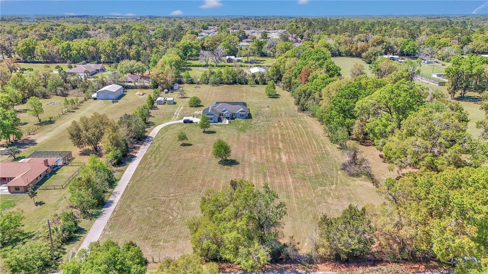 5+ Acre Estate with Heated Pool, Mother-in-Law Suite & Modern Amenities – Minutes from Downtown Ocala! Discover the perfect combination of luxury, space, and convenience in this breathtaking 2,400+ SqFt home. This meticulously maintained estate offers everything you need for refined country living with modern comforts. Experience an expansive open-concept living, dining, and kitchen area with soaring 10-foot crown molded ceilings, creating a bright and airy atmosphere. This custom design offers both elegance and functionality, perfect for entertaining or everyday luxury. A modern chef’s kitchen at its heart, a grand sit-in island serves as both a stylish centerpiece and a practical workspace, featuring cabinet storage underneath—perfect for keeping cookware, appliances, and pantry essentials neatly tucked away. The sleek marble countertops add a touch of sophistication, their smooth veining complementing the high-end finishes throughout the space. For those who love to cook, the double built-in wall ovens allow the convenience of preparing multiple dishes at once, making meal prep effortless for family dinners or large gatherings. The home also includes a built-in speaker and surround sound system, allowing you to enjoy high-quality audio throughout the space. 3 spacious bedrooms and 3 full bathrooms, including a private Mother-in-Law suite—ideal for guests or multi-generational living. Primary suite offers tiled flooring, and range to fit a full king sized bedroom set, complimented by dual walk-in closets. The master en suite is a true retreat, featuring a 6-ft soaking tub for ultimate relaxation, tiled stand up shower, and double sink vanity. The finished garage provides ample storage with built-in cabinets, shelving and tiled flooring, offering a clean and organized space for your tools, toys, or hobby setup. Outside, enjoy your private 16x32 in-ground heated pool with an extended concrete patio surrounding, and spa like hot tub. The perfect lanai for year-round swimming and entertaining. The fully fenced property features an automatic gated entry for added security and privacy, along with a security system and cameras for peace of mind. Enjoy 5 acres of versatile land, perfect for outdoor entertaining, recreational activities, gardening, future expansion, and plenty of established pasture for your horses. This energy-efficient home is powered by solar panels, keeping utility costs low, while a tankless water heater ensures endless hot water. As an added bonus, the seller is offering the option to purchase the home fully furnished, so you can move in and start enjoying your new oasis immediately! All located just 15 minutes from downtown Ocala, less than 30 minutes from the World Equestrian Center and within a drives reach of Ocala national park / recreational areas. Don’t miss this incredible opportunity to own a truly one-of-a-kind property in a prime Ocala location.
