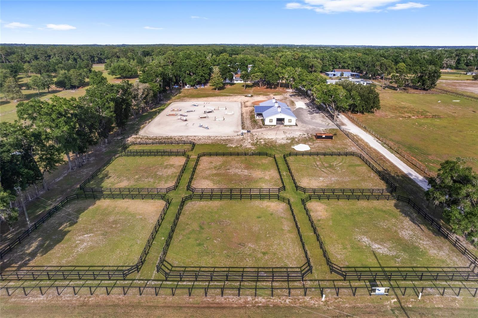 EXCEPTIONAL EQUESTRIAN ESTATE
Positioned directly across from the renowned World Equestrian Center in the heart of Ocala, Florida — the Horse Capital of the World — this extraordinary estate represents a rare opportunity to own a world-class equestrian property at the epicenter of the sport.
Equestrian Facilities
The barn and riding arena were custom built in 2025 by Jim Ballinger of M&W Building Solutions, reflecting the highest standards of craftsmanship and equestrian design. Constructed of solid cinderblock with a double-insulated roof and French drain gutters, the barn is engineered to handle Florida's heavy rainfall while keeping the interior dry and comfortable year-round.
The professional-grade barn features 12 spacious 12' x 14' stalls, each equipped with individual fans, fly spray systems, and automatic waterers. Three cupolas and large industrial overhead fans ensure exceptional airflow throughout. Yoke windows along the aisle and exterior shuttered windows flood the space with natural light while maintaining a classic equestrian aesthetic. Two roll-up end doors and a euro-style slide entrance add everyday convenience for equipment, hay delivery, and vehicle access. The barn is further appointed with two interior wash racks with hot and cold water, a tack room, feed room, laundry room, bathroom, and kitchenette.
Riding Arena & Paddocks
The impressive 150' x 250' all-weather riding arena features a full irrigation system and concrete curb, providing premier footing year-round. Two interconnected water wells — including a dedicated 5 HP well powering arena irrigation — ensure a reliable water supply at all times. Seven irrigated paddocks, freshly reseeded and fully fenced with hot-wired fence boards, offer safe, lush turnout for your entire herd.
Residential Accommodations
The main residence offers 6 bedrooms and 3.5 bathrooms, completely remodeled in 2025 — professionally decorated and furnished by an interior designer with all new appliances — delivering generous spaces for everyday comfort and entertaining. Bedroom views overlooking the barn, arena, and paddocks offer a truly immersive equestrian living experience. Beautifully appointed patio areas extend living space outdoors, perfect for relaxing while taking in the serene surroundings. A newly installed gated entrance and paved parking area offer security and a polished first impression. Multiple dwelling units provide flexibility — ideal for guest quarters, staff housing, multigenerational living, or income-producing opportunities.
Expansion Opportunity
Favorable zoning presents exciting possibilities — including the ability to build an additional residence, plus dedicated structures for hay storage and equipment. Whether expanding the operation or creating a multigenerational compound, the groundwork is already in place.
Location
At the heart of Ocala's premier equestrian corridor, this estate places you steps from the World Equestrian Center — whether you're an active competitor, dedicated breeder, or someone who appreciates the finest in equestrian living, this location puts you at the center of it all.