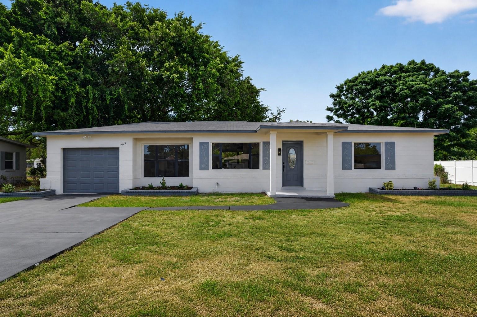 Welcome to this beautifully renovated 3-bedroom, 2-bathroom home in the established Bay Vista Park neighborhood of St. Petersburg, with no HOA. Set on a .26-acre lot with a deep, open backyard, this move-in-ready home blends modern finishes with comfortable, functional living. Inside, luxury vinyl plank flooring runs throughout an open-concept layout that flows from the living and dining areas into a fully renovated kitchen featuring quartz countertops, a full quartz backsplash, stainless steel appliances, white cabinetry, and matte black fixtures. Large windows fill the home with natural light. Both bathrooms are fully updated with designer tile, modern vanities, backlit LED mirrors, and black rainfall fixtures, and the primary bedroom includes a walk-in closet. Step out to the covered rear patio overlooking a large, tree-shaded backyard with plenty of room for outdoor dining, pets, gardening, or a future pool. An attached one-car garage adds everyday convenience. Ideally located minutes from downtown St. Petersburg, I-275, shopping, dining, and area parks. Schedule your private showing today.