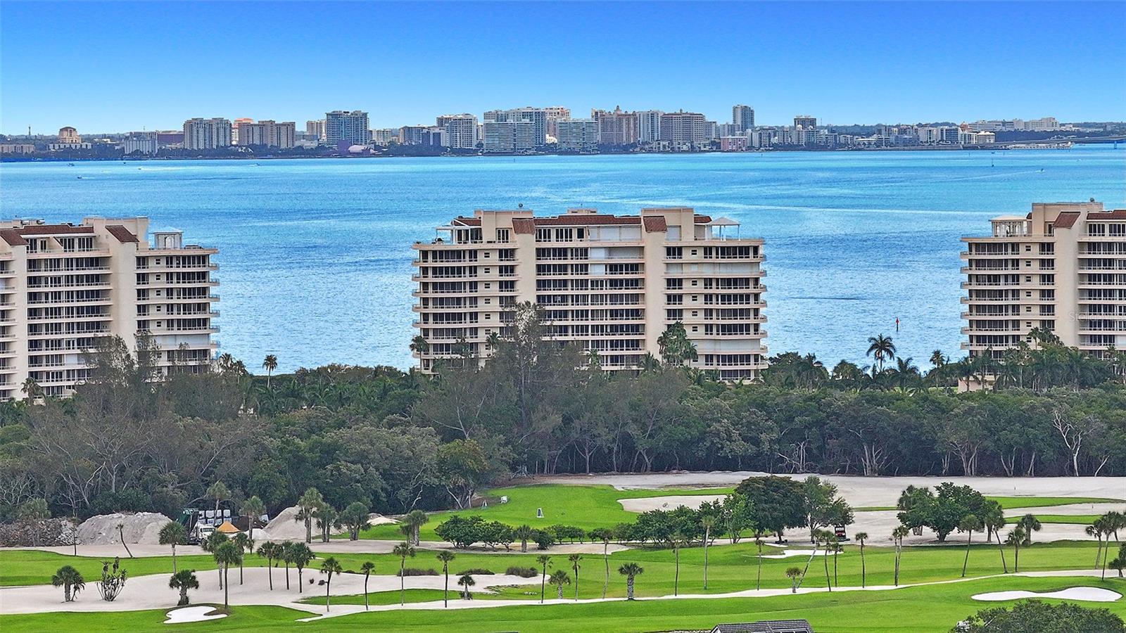 Welcome to a world of luxury and refinement in this 3BR/3.5 BA masterpiece of 2,925+/- sq. ft. in the prestigious Grand Bay community on Longboat Key. From the private elevator lobby, step through the elegant double doors and be captivated by the sumptuous style, with rich wood floors that enhance the stunning blues and greens visible through expansive walls of glass. Positioned on the south side corner of Building 3, this residence offers one of the most spectacular views in all of Grand Bay, offering a visual feast of sunrises over the bay and sunsets beyond the Gulf. Gaze out at the marina from this prime 8th-floor vantage point. The updated kitchen has quartz countertops, top-of-the-line Bosch appliances and an adjacent eat-in area framed by stunning vistas. Each bedroom is a private enclave with its own bathroom en-suite, while the master suite is a lavish escape, featuring access to the open terrace and an opulent master bathroom with a spa tub, glass walk-in shower and a fabulous ceiling light fixture. The voluminous, custom walk-in closet caters to your dressing needs. The crown jewel is the expansive wraparound terrace, an idyllic setting for hosting or unwinding, with the bay’s shimmering waters extending into the horizon. Additional features include two secure parking spaces, electric storm shutters throughout, a beverage bar with wine cooler, a new 5-ton A/C system and a laundry room equipped with newer Whirlpool front load washer and dryer. Residents of Grand Bay enjoy a host of amenities, including a 24-hour guard gate, clubhouse, fitness center, 2 Har-Tru tennis courts, 2 heated pools and a spa. Deeded access to the private beach is close by.