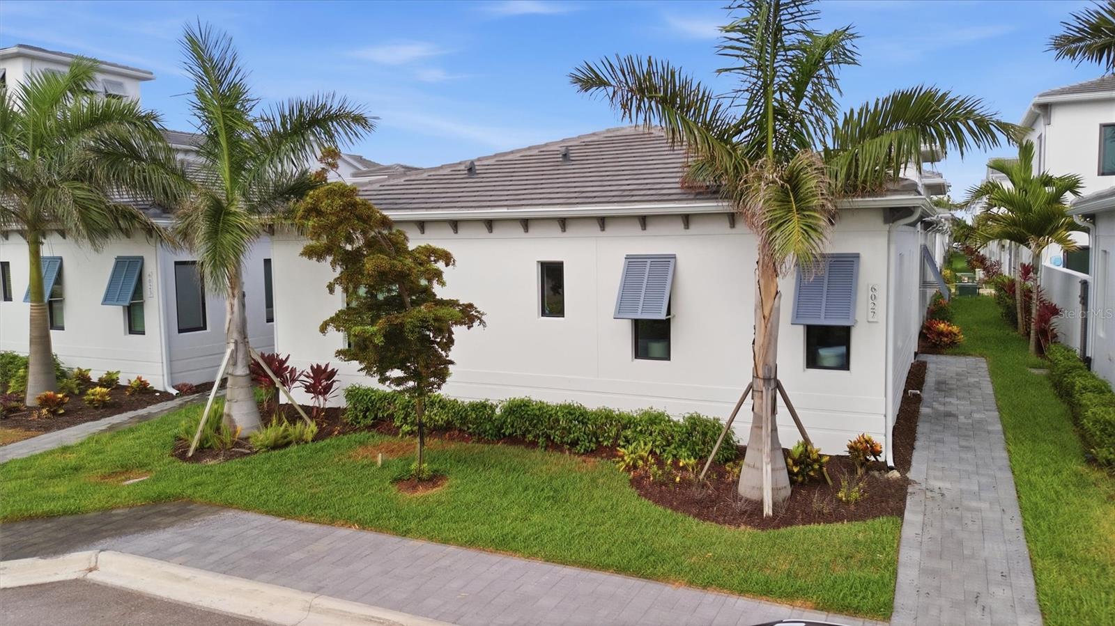 Welcome to this stunning Sea Grape floorplan in the highly sought-after Aqua Lagoon community, where luxury, comfort, and resort-style Florida living come together. Perfectly situated near the scenic shores of Sarasota Bay, this exceptional neighborhood is centered around a breathtaking four-acre, crystal-clear blue lagoon with a private tropical shoreline—bringing the beach right to your backyard. Built in 2024, this beautifully designed 3-bedroom, 3-bathroom residence offers 2,464 square feet of thoughtfully crafted living space centered around a private screened heated pool, creating the perfect setting for entertaining or everyday relaxation.

Designed with a courtyard centered floor plan, the home features soaring ceilings, abundant natural light, and seamless transitions between the main living areas. The spacious living room flows effortlessly into the gourmet kitchen, complete with custom cabinetry, premium stainless-steel appliances, a built-in oven and microwave, gas cooktop, generous center island with seating, and abundant prep space for both everyday living and entertaining.

The primary suite serves as a private retreat with direct access to the pool courtyard, a spacious walk-in closet, and a spa-inspired en-suite bath featuring dual vanities, a soaking tub, and a separate walk-in shower. A second bedroom and full bathroom are conveniently positioned near the front of the home, offering flexibility for guests or a home office, while the third bedroom is privately situated with its own en-suite bath, creating the perfect setup for visitors or multigenerational living.

Step outside to your own private oasis, where the screened courtyard showcases a heated pool designed for year-round enjoyment. Whether you're enjoying your morning coffee, hosting friends and family, or unwinding after a day on the water, this inviting outdoor space extends your living area and embodies the best of the Florida lifestyle.

Additional highlights include a rear-entry oversized two-car garage, mature tropical landscaping, quality finishes throughout, and a thoughtfully designed floor plan that offers both privacy and functionality. For buyers seeking a truly move-in-ready experience, the home's designer furnishings are negotiable, presenting a rare opportunity to enjoy this exceptional residence fully furnished.

Residents of Aqua Lagoon enjoy exclusive access to the community's spectacular crystal-clear lagoon, complete with a private sandy beach and opportunities for swimming, kayaking, paddleboarding, or simply relaxing in a true resort-style setting. Combined with its ideal West Bradenton location, you'll be just minutes from IMG Academy, IMG Golf & Country Club, Anna Maria Island, Cortez Fishing Village, Sarasota-Bradenton International Airport (SRQ), and the shopping, dining, and entertainment destinations of UTC and St. Armands Circle.

Whether you're searching for a primary residence, seasonal escape, or investment opportunity, 6027 Salt Grass Street offers an exceptional combination of luxury, location, and lifestyle in one of West Bradenton's most unique waterfront-inspired communities. Schedule your private showing today.