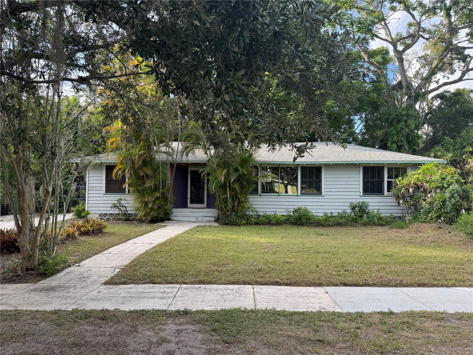 The property's unique RTD-9 zoning offers flexible zoning for some specific commercial businesses. Please inquire for more information. This vintage Ringling area home offers a unique floor plan with ample opportunities for customization. Located just minutes from downtown, the SRQ Airport, Ringling College, USF, New College, and numerous entertainment venues nestled on a tranquil street.
Upon entering the home, you will be captivated by its architectural features reminiscent of a bygone era. The open eave overhang, cypress siding, and wood windows are among the standout details that contribute to its distinct character.
The foyer welcomes you with original heart pine floors that extend throughout the floor plan. The living room boasts a spacious picture window overlooking the front yard and a cozy fireplace surrounded by shelves. The master bedroom is generously sized to accommodate a king-size bed, providing ample space for a sitting room that extends to a lush green backyard.
The kitchen/dining room on the opposite side of the home is filled with natural light, creating an ideal setting for entertaining. Its spacious layout allows for the transformation of the kitchen into a true chef’s kitchen.
A private hallway off the kitchen leads to the second and third bedrooms. The backyard, akin to a private paradise, features a diverse array of trees and a custom-built open carport/workshop.
Schedule a viewing of this exceptional home today.