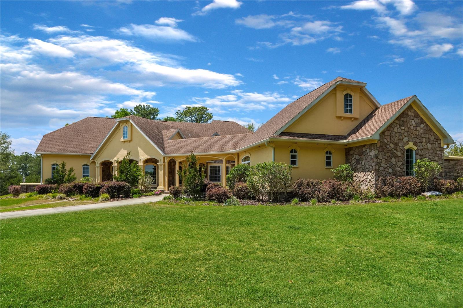 Set behind a private electric gate on 5 acres, this extraordinary estate offers a rare blend of luxury, self-sufficiency, and peaceful rural living—without sacrificing convenience. Thoughtfully designed for off-grid capability, the property is equipped with a solar grid, backup propane generator, and extensive infrastructure, creating a truly resilient and sustainable retreat. A paved drive leads through the property, complete with an underground sprinkler system and a striking three-tier water fountain, setting the tone for the craftsmanship found throughout. The stately main residence features 4 bedrooms, 3 full baths, and 2 half baths, complemented by a private mother-in-law suite, expansive barn, and a charming guest house with 350 square feet of heated and cooled space—ideal for visitors, extended family, or a home office. Inside, the home showcases a spacious open floor plan with granite countertops, oak cabinetry, generous walk-in closets, and abundant natural light. A downstairs primary suite offers comfort and privacy, while the upstairs library/office and wet bar create ideal spaces for work and entertaining. Designed for those who love to host or unwind outdoors, the home boasts over 1,500 square feet of open porches plus a 739-square-foot screened porch, perfect for enjoying serene views and quiet moments surrounded by nature. Quality construction and energy efficiency are evident throughout, including Pella energy-efficient windows (2019), masonry block walls, concrete slab foundation, and spray foam insulation for year-round comfort. Additional features include a 200-bottle wine cooler, wired security system with video cameras, 15-KW propane generator with transfer switch, and a separate solar transfer system—providing true peace of mind. Despite its private, pastoral setting, this exceptional property is conveniently located just minutes from I-75, Gainesville, Lake City, and High Springs, offering quick access to shopping, dining, medical facilities, and entertainment. This is more than a home—it’s a lifestyle. A rare opportunity to own a legacy property where luxury, sustainability, and tranquility come together in one remarkable estate. **Seller has it listed with the full 66+ acres as well. MLS GC535301.