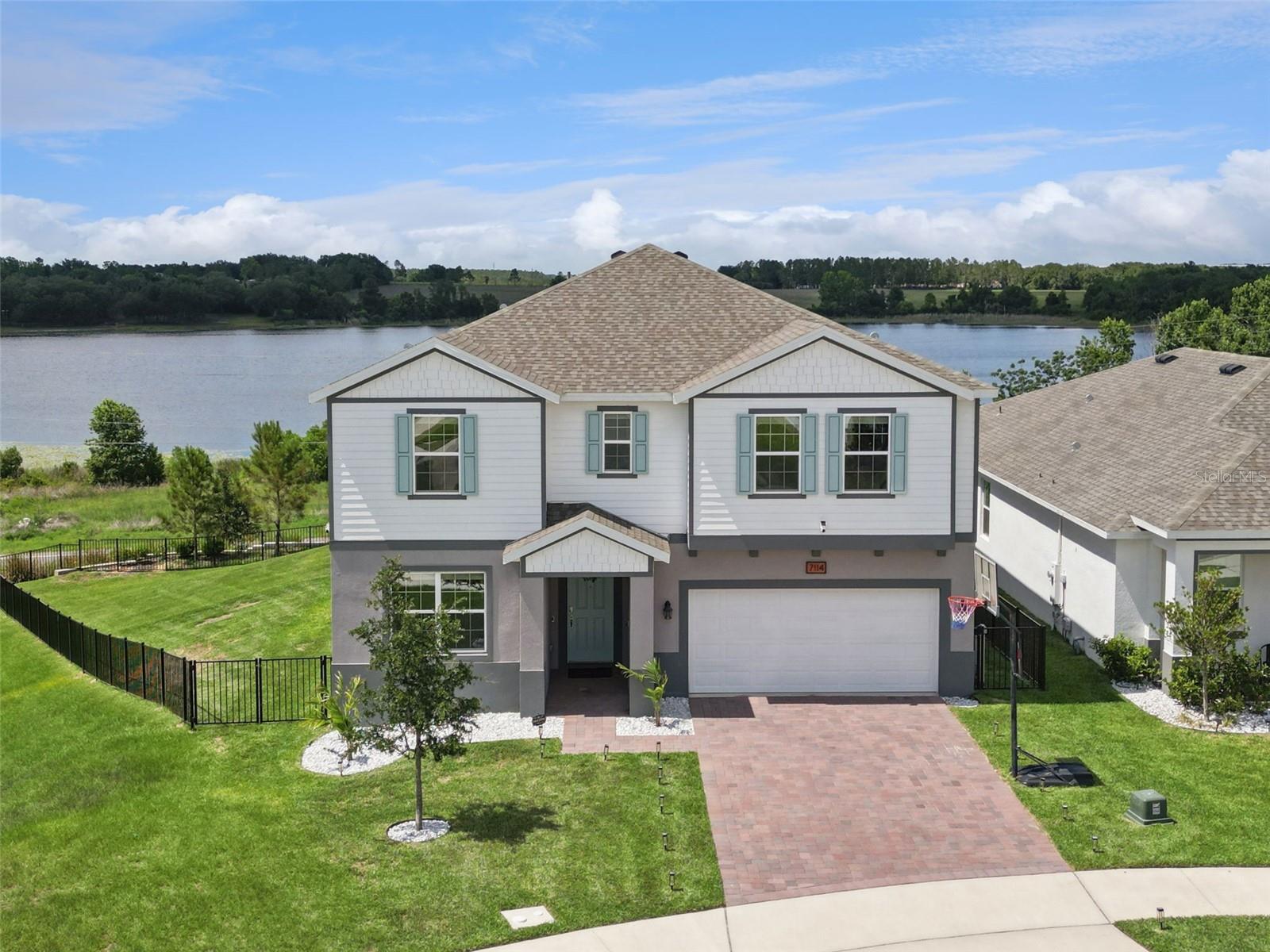 Newer construction home with all the upgrades and none of the wait time? Yes, please!! Welcome to this beautifully upgraded home situated on one of the most desirable homesites in the community. Positioned on a large corner lot this property offers no rear neighbors, only one side neighbor, and stunning unobstructed lake views that create a peaceful backdrop for everyday living. Located alongside a walking trail, the setting combines privacy, outdoor enjoyment, and scenic surroundings. Inside, the thoughtfully designed floor plan features spacious living areas, a large second floor loft, and a convenient upstairs laundry room. The kitchen is equipped with wood cabinetry, granite countertops, and ample workspace, while granite countertops continue throughout all bathrooms. Tile flooring extends throughout the downstairs living areas, with luxury vinyl plank flooring in the upstairs common spaces. Carpet is reserved for the bedrooms, creating comfort where it matters most. Additional builder upgrades include an enhanced elevation, upgraded flooring, added lighting, an extended lanai, and an oversized 12 foot sliding glass door that fills the home with natural light and showcases the lake views. Outdoor living is a standout feature of this property. The fully fenced backyard includes an oversized covered lanai, extended paver patio, reinforced pergola posts ready for future completion, solar powered bistro lighting, and a stone fire pit, creating an ideal space for relaxing or entertaining while enjoying the water views. White rock landscaping and Adonidia palm trees enhance the curb appeal and outdoor atmosphere. Additional highlights include a water softening and filtration system with reverse osmosis drinking water, solar powered exterior security cameras, Ring doorbell, upgraded lighting fixtures throughout, and a fence with a lifetime warranty. Major systems including the roof, air conditioning system, and water heater were installed in 2025. The transferable builder warranties provide added peace of mind, including remaining structural coverage. This exceptional property combines modern upgrades, outdoor living, and one of the largest and most private lots in the neighborhood.