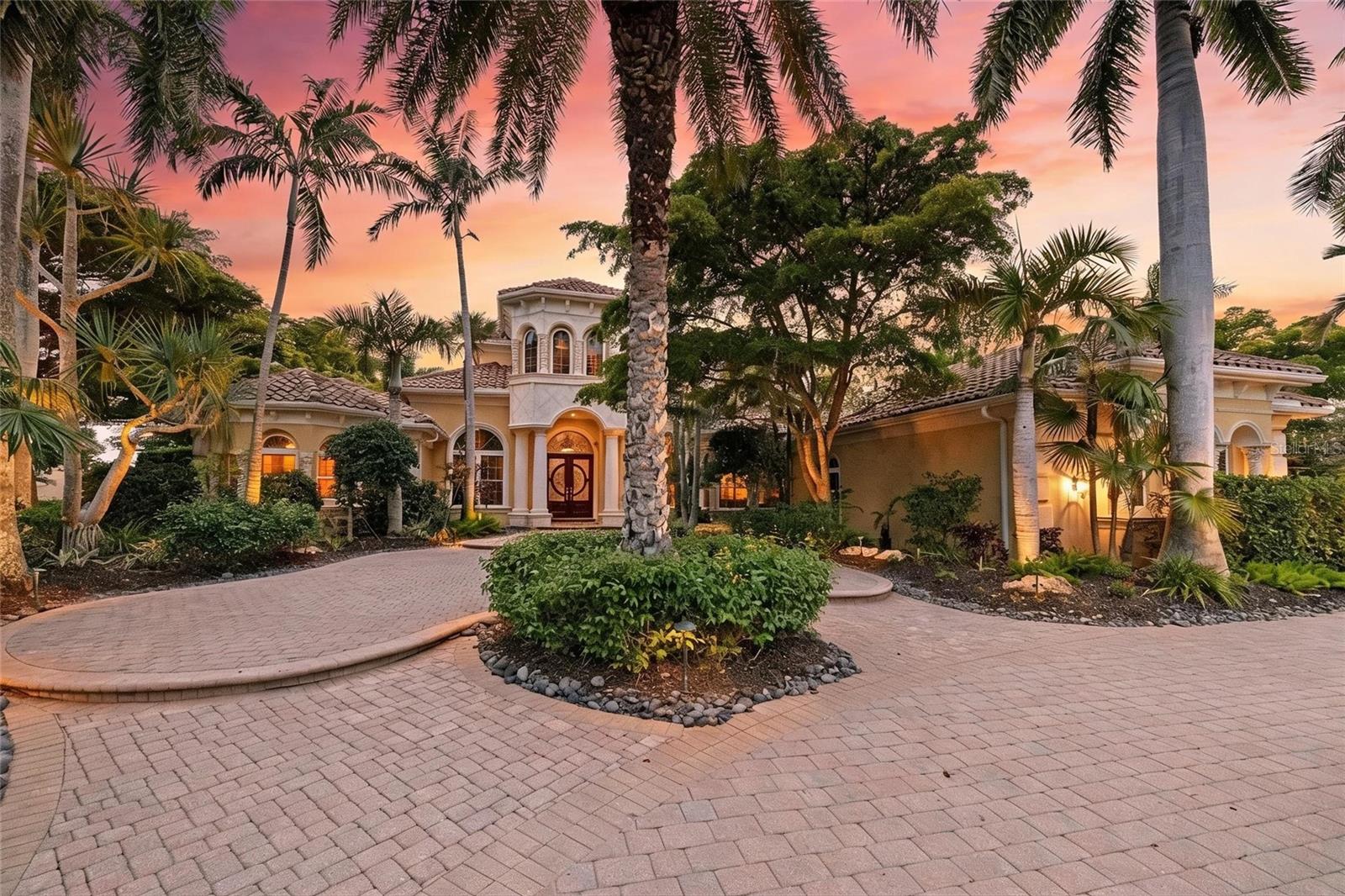 Set on more than half an acre with sweeping golf course views, this extraordinary custom estate by award-winning Pruett Builders is a masterclass in Mediterranean elegance and resort-style living. Tucked within prestigious Lakewood Ranch Country Club, the residence blends architectural artistry, refined craftsmanship, and effortless indoor-outdoor flow.
Mature royal palms and lush landscaping frame a circular paver driveway with a striking compass-rose medallion, leading to a grand columned portico and arched mahogany doors set with beveled leaded glass. Inside, a stunning foyer welcomes you with fluted columns, marble flooring, and a custom mosaic medallion underfoot.
The home's centerpiece reveals itself just steps inside: a breathtaking two-story rotunda anchored by a domed coffered ceiling, crystal chandelier, and soaring arched windows that frame serene views of the lanai and golf course beyond. A dramatic curved wood staircase sweeps to the second level, where a balustraded gallery showcases a custom-built library with floor-to-ceiling bookshelves.
The gourmet kitchen is a chef's sanctuary with custom wood cabinetry, granite countertops, and mosaic tile accents framing a sculptural stone hood. A GE Monogram 6-burner gas range with double ovens, paneled refrigerator and freezer, warming drawer, pot filler, and center island anchor the space, complemented by a walk-in pantry and butler's pantry. The adjoining gathering room flows outdoors through expansive pocketing sliders.
The owner's suite is a private sanctuary with sitting area, plantation shutters, double tray ceiling, and his-and-her walk-in closets with wood built-ins, personal steamer, and ironing center. The spa-inspired bath features a domed ceiling with crystal chandelier, granite vanities, custom maple cabinetry, octagonal marble mosaic floor inlay, walk-through shower, and Jacuzzi tub.
Upstairs, accessible by the curved staircase or private wood-paneled elevator, a spacious game room with wet bar, granite counters, wine cooler, and dishwasher opens to a balcony overlooking the pool and fairways. Additional spaces include a fitness room. guest suite, full bath with steam shower, and dedicated home theater with projector.
Outside awaits a true private resort. A panoramic screened enclosure frames a heated saltwater pool and elevated spa with cascading water feature, all set against graceful Mediterranean arches opening to unobstructed golf course vistas. The veranda and outdoor kitchen feature granite counters, bar seating, refrigerator, grill, sink, and fireplace with cast coral stone surround beneath Cypress wood ceilings; with a spiral staircase to the upper balcony.
Additional luxuries include impact-resistant windows and doors, whole-home surround sound, security system, smart home setup with Control 4, central vacuum, and a 4-car garage with built-ins and epoxy flooring.
More than a residence, 7202 Teal Creek Glen is a statement of refined living, where award-winning craftsmanship and unforgettable indoor-outdoor spaces converge in one of Lakewood Ranch's most coveted enclaves.
