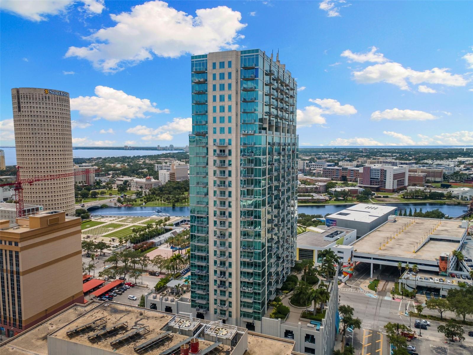Welcome to a life of elevated urban luxury at SkyPoint, where the city’s most breathtaking views become your everyday backdrop. This rare 25th-
floor corner residence has been completely reimagined by one of Tampa’s premier interior designers, offering a gorgeous two-bedroom, two-
bathroom sanctuary. Ten-foot floor-to-ceiling windows frame unforgettable southern exposures of the downtown skyline, Tampa Bay, the
Hillsborough River, and the Garrison Channel, inviting you to greet the day with majestic sunrises from your private balcony. The transformation
is immediate, with wide-plank flooring flowing throughout the main living areas and plush carpeting in the bedrooms, all selected for modern
elegance. The thoughtful redesign includes integrated remote-controlled sunshades and a spacious layout perfect for both grand entertaining and
daily living, featuring a dedicated dining area and an oversized laundry room with ample storage. The renovated kitchen is a highlight, appointed
with fresh quartz countertops, a sleek tile backsplash, new stainless-steel appliances, and a central island. Your residence includes two
conveniently assigned parking spaces on the third floor of the secured garage. SkyPoint itself redefines resort-style living, with a 24-hour
concierge and controlled access ensuring privacy and security. The eighth-floor amenity deck features a heated pool, a saltwater hot tub, multiple
outdoor grilling stations, an outdoor kitchen, and a beautifully landscaped park in the sky. Inside, find a state-of-the-art dual fitness center, a
residents' clubhouse with a catering kitchen and bar, lounges, and a private theater room. Embrace the vibrant energy of downtown Tampa from
your front door, with the cultural arts district, Curtis Hixon Park, and the Tampa Riverwalk directly outside. You are moments from the city's best
attractions, with easy access to the trolley, water taxi, and Tampa International Airport. This meticulously renovated residence is your gateway to
the very best of Tampa, offering a turnkey experience in a world-class location.