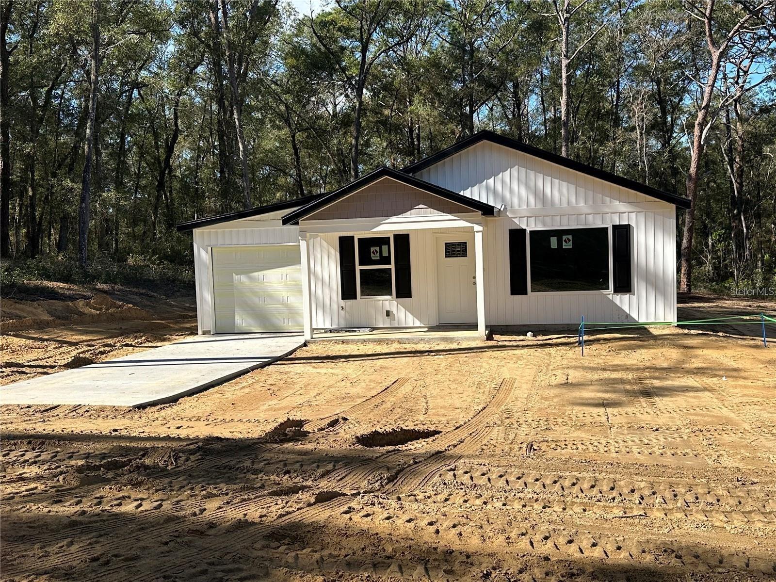 Under Construction. Now offering Down Payment assistance with approval. Welcome to this exciting new construction project, a charming and affordable cottage home in the desirable Rolling Ranch Estates neighborhood, just a quick drive to the scenic Rainbow River. This home offers an excellent opportunity to experience comfortable living with its well-designed features. Key Features: Spacious Rooms: Enjoy the luxury of generously sized rooms, providing plenty of space for relaxation and everyday activities. Open Kitchen: The home features an open kitchen layout, creating a seamless flow between the kitchen and living areas, perfect for entertaining and family gatherings. Elegant Kitchen Upgrades: The kitchen will showcase granite countertops, adding a touch of elegance to your culinary space. Stainless steel appliances provide modern convenience and functionality. Stylish Flooring: The choice of vinyl plank flooring enhances the home's aesthetic appeal while offering easy maintenance and durability. Country Porch: Picture yourself unwinding on the charming country porch located at the front of the home. It's an ideal spot to enjoy the neighborhood atmosphere and relax outdoors. Unique Roof Design: This home stands out with its 6' 12" pitch roof, adding character and curb appeal, making it one of the most adorable houses in the neighborhood. Three Bedrooms, Two Bathrooms: With three bedrooms and two bathrooms, this home offers a comfortable living space, providing ample room for residents and guests. 1-Car Garage: The inclusion of a 1-car garage provides convenient parking for your vehicle and additional storage space. Cleared Land: The property's land is already cleared, laying the foundation for a smooth and timely construction process. Please note that the home is currently under construction. While pictures and virtual tours are available to offer an accurate depiction of the completed home, there might be slight variations in interior colors. Given its appealing features and prime location near Rainbow River, this home is expected to sell quickly. Don't miss out on the opportunity to own a lovely cottage home in Rainbow Park—an alternative to tiny home living without compromising on the number of bedrooms. This model has the current changes, Premium siding on the front, added a back door, and a back wood deck patio. Color is White and Black Trim.