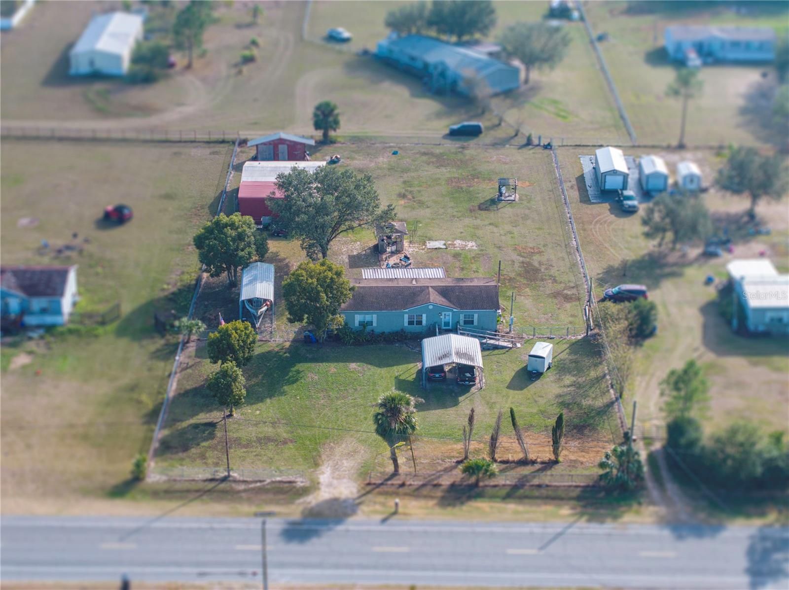 Enjoy peaceful country living in this 3/2 doublewide on 1.03 acres with open floor plan, high ceilings & enclosed patio. Fully fenced with 2 drive-through gates. Features gazebo w/electric, firepit & large covered area for vehicles/toys. Includes 24x30 workshop, 20x30 carport, add-on bldg w/electric & water, well pump house & 25 yd shooting range pergola. 50-amp RV/generator hookup. Updates: roof 2014, A/C 2018, well & septic 2022, dishwasher & dryer 2024. This property offers a rare combination of space, functionality, and outdoor amenities, perfect for those seeking privacy, hobbies, or room to grow.