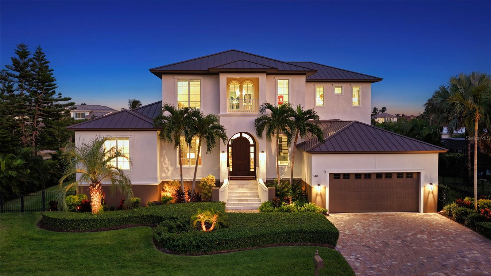 This exquisite home is sure to exceed expectations! This exceptional 4 bed/5 bath canal-front estate is located in coveted Country Club Shores, where chic architecture, thoughtful craftsmanship, and effortless coastal luxury converge. Designed by DSDG architects to maximize the contemporary sightlines and southern exposure, this Voight built custom residence offers a spectacular open floor plan and is positioned just three lots from the open waters of Sarasota Bay.  This extraordinary residence is better-than-new with a recently installed metal roof, AC systems, and whole home generator and has been impeccably maintained. The home has been built to effortlessly withstand the Florida coastal environment while maintaining its magnificent beauty and clean lines. Boaters will appreciate the Trex dock equipped with a 20,000-lb boat lift, kayak and paddleboard racks, and convenient launch deck - providing quick, easy access to bay and Gulf waters. Inside, the home is both stunning and impressive with exquisite finishings and custom millwork. The first-floor owner’s suite is a luxurious retreat highlighted by soaring triple-coffered tray ceilings, tranquil views, and private pool access for a midnight swim. The spa-like bathroom is pure luxury. The chef’s kitchen is a true showpiece, featuring Viking appliances, a Sub-Zero Pro refrigerator, a walk-in pantry, expansive countertops, and a dramatic 14-foot quartz island perfect for large gatherings. The integrated dining area is framed by an aquarium window which emphasizes the tranquil water views. The family room is a natural extension of the kitchen and provides a generous area with direct access to the lanai, grille and dining areas and is perfect for enjoying movies, or just gathering with friends and family. The great room is spacious with large archways, gas fireplace, custom built-in shelving, and coffered shiplap ceilings which add to the drama of this cozy but elegant space. A wall of windows provides access to the covered lanai area and expands the feeling of openness highlighting the pool, sparkling spa, and water views. The second floor has been completely reimagined to elevate both style and function, offering three private guest suites, a versatile and spacious Florida room, wet bar, and a 300+ bottle state-of-the-art walk-in wine cellar. The enclosed upper lanai enhances ambiance and panoramic views. The Florida room provides a flexible space for enjoying sporting events or wine tastings, and includes a full bath for convenience. The 3 bedrooms on the second level are generous in size and 2 of the 3 include ensuite baths. Outdoor living is equally exceptional. The lanai with a Cypress-clad ceiling includes a new grill and dining area and pool bath, which steps down to the saltwater pool, spa, and sun deck - an ideal setting for entertaining or enjoying sunshine year-round. Additional features include a two-car garage with generous overhead storage, a rear enclosed storage compartment, and an electric vehicle charger. There is ample vertical height in the garage to add a car lift as an option. Residents of Country Club Shores enjoy private deeded beach access to the Gulf of Mexico, with optional golf and tennis memberships available at the nearby Resort at the Longboat Key Club. This is waterfront living at its finest - refined, relaxed, and designed to be enjoyed. A must-see property to fully appreciate the exceptional lifestyle, upgrades, and craftsmanship throughout.