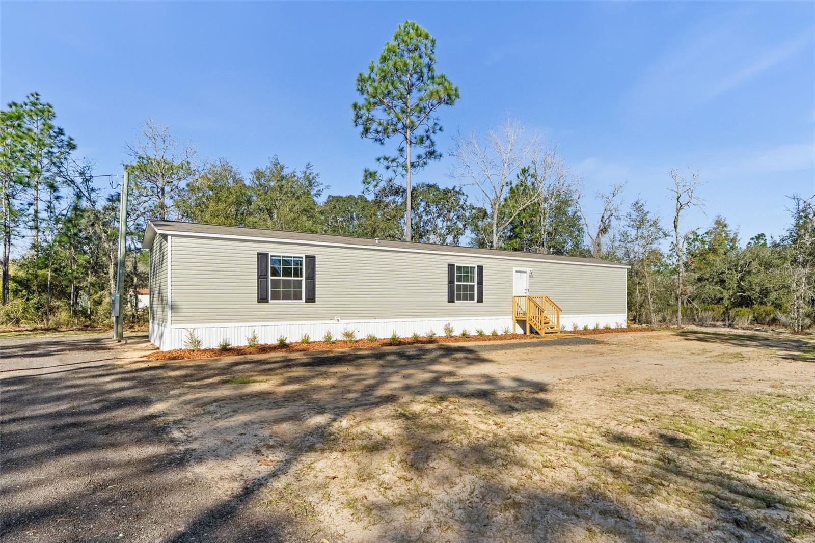 Brand-new 3BD/2BA Champion manufactured home on .92 acres in Bronson, FL—move-in ready and thoughtfully designed for comfort, efficiency, and durability. Offering 1,153 sq. ft. of well-planned living space, this home is built to Wind Zone II standards and Energy Star certified, providing peace of mind and long-term value. The open-concept layout seamlessly connects the kitchen, dining, and living areas, creating a bright and functional gathering space. The kitchen is equipped with Whirlpool appliances, including a range/hood, refrigerator, and dishwasher. Additional features include an energy-efficient Rheem hot water heater, a brand-new well and septic system, fresh millings driveway, professional landscaping for curb appeal, and a one-year home warranty. Enjoy the tranquility of rural living while remaining conveniently close to Gainesville for shopping, dining, healthcare, and entertainment. Outdoor enthusiasts will appreciate nearby attractions such as Devil's Den Spring, Black Prong Resort, Cedar Lakes Woods and Gardens, and the Goethe State Forest. Notably, this property is located next door to another newly constructed manufactured home currently available for separate purchase, presenting a unique opportunity for buyers seeking multi-generational living, extended family proximity, or investment flexibility—while still enjoying the privacy of separate parcels. Schedule your private showing today and experience the perfect blend of modern amenities and country charm at 5370 NE 108th Ter, Bronson, FL 32621.