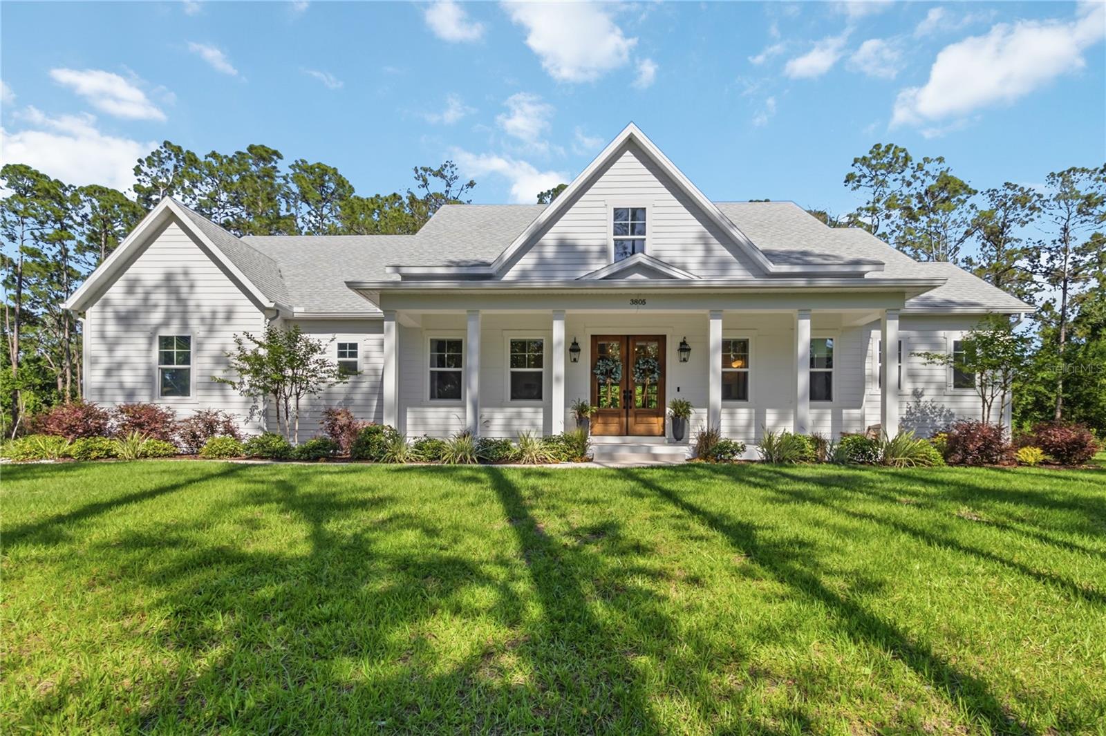 Custom-built home situated on over an acre with no HOA, offering 5 bedrooms, a den/flex office space, 3.5 bathrooms, and a side-loaded 3-car garage. The property welcomes you with an oversized front rocking porch and impressive curb appeal. At the rear of the home, enjoy a premium saltwater pool, an oversized deck, and an expansive paver-covered lanai designed for outdoor living and entertaining.

Upon entry, the attention to detail in this custom build is immediately evident, featuring luxury vinyl flooring throughout the main living areas, carpet in select bedrooms, and upgraded fixtures throughout the home. The kitchen is truly the centerpiece, showcasing quartz countertops, expanded cabinetry, a stainless steel appliance package, natural gas cooking, a custom range hood, and glass accent cabinet doors.

The primary suite is located on the main floor and offers private access to the lanai and pool area. The spa-like primary bath features a soaking tub, oversized shower, dual sink vanities, and a premium walk-in closet with a window nook for natural light. Two additional bedrooms are also located on the main floor and share a private Jack-and-Jill bathroom. The laundry room and convenient drop station are thoughtfully positioned in this section of the home.

Upstairs, you will find a generous loft area that works perfectly as a second living room or flexible entertainment space. On opposite sides of the loft are two additional bedrooms, providing privacy and comfort for family members or guests. 

The expansive lot offers over an acre of space with access from both the corner and cross street, providing flexibility for adding an exterior building, workshop, or studio. The home is highly efficient and also offers a 24w whole house generator system. The area also offers nearby lake access through a public boat ramp or community landing. This property combines luxury finishes, thoughtful design, and exceptional indoor and outdoor space—truly a home that must be seen to be fully appreciated.