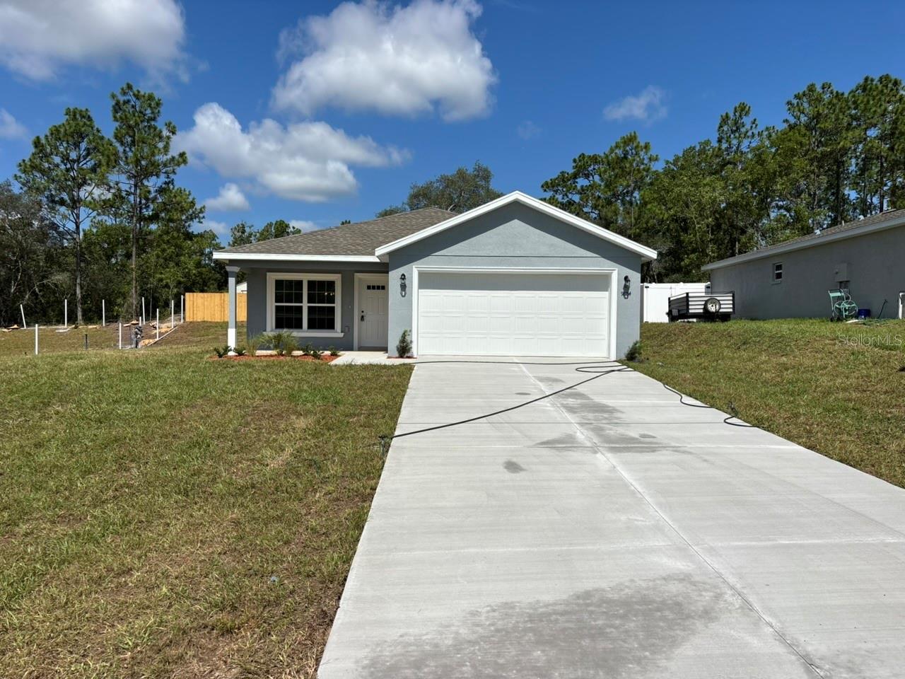 NEW CONSTRUCTION. MOVE-IN READY! This New Anastasia Model in Citrus Springs offers 3 bedrooms, 2 bathrooms, 1,409 square feet of living space, and a total of 2,057 square feet, with a smart, comfortable layout. Built with concrete block construction, a 30-year architectural shingle roof, energy-efficient double-pane windows, and a 10-year structural warranty, this home is designed for lasting quality and peace of mind. Inside, you will find luxury vinyl plank flooring in the main living areas and bedrooms, stainless steel appliances, custom white shaker cabinets with soft-close drawers, and granite countertops in the kitchen and bathrooms. The primary bedroom features a tray ceiling with crown molding and a large walk-in closet, while the primary bathroom includes a large shower and a double vanity with granite countertops. The second bathroom includes a tub with a shower and a single vanity with granite countertops. Additional features include multiple storage closets, a dedicated laundry room with washer and dryer hookups, covered front and rear porches, and an attached 2-car garage with opener and remotes. Enjoy ownership freedom with no HOA fees, plus a high and dry flood zone X location with no flood insurance required.