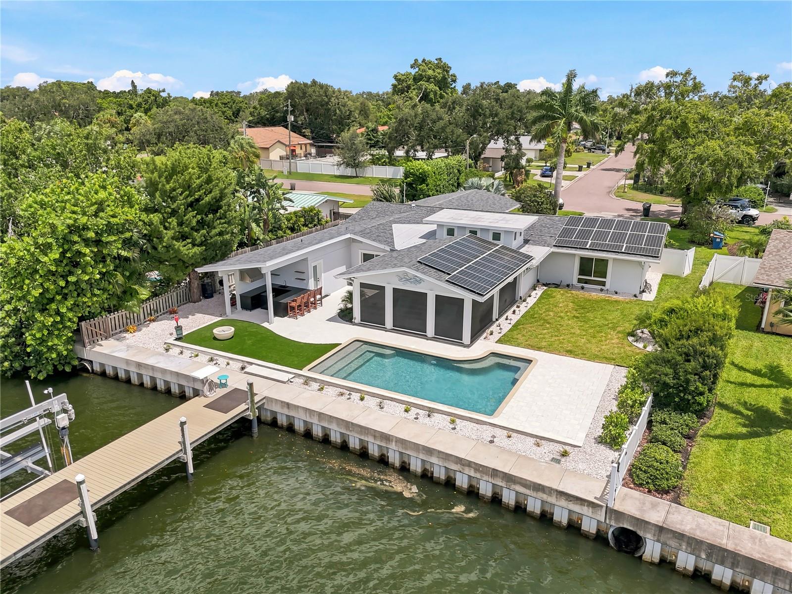 Welcome to a premier Broadwater waterfront sanctuary—where the art of entertaining meets the boater's dream. This meticulously updated one-story residence spans 2,957 square feet of refined living across 3 bedrooms and 2.5 baths, positioned on an expansive 84 x 140 lot that commands deep-water channel access and easy passage to Boca Ciega Bay and the Gulf. Whether you're launching for an early morning fishing expedition or hosting sunset cocktails, this property has been reimagined for the discerning lifestyle enthusiast. The 2026 kitchen renovation speaks luxury: quartzite countertops and backsplash; Wolf 48-inch dual fuel range with built-in flattop and grill; 48-inch Wolf hood; paneled Subzero refrigerator with separate wine fridge, 30” refrigerator and 24” Freezer; a Miele coffee system with water supply; Cove dishwasher; wet bar with a Scotsman pellet ice maker;  and a generous hidden walk-in pantry. That philosophy extends to the full outdoor kitchen featuring a Blaze 36-inch grill and Azure wine fridge, framed by artificial turf, landscape lighting, and a fire pit for evening gatherings. The saltwater, solar-heated Pebble Tec pool and new pool bath complete the resort-style setting. The primary suite welcomes you with a spa-like walk-in shower, its Toto washlet complementing the luxury spa experience, alongside a double walk-in custom closet offering refined storage. Entertainment space abounds with large living room, 2nd sitting area and covered lanai with electronic roll up screens.  Two additional bedrooms in the split plan are next to the luxurious updated hall bath. Beyond entertainment, this home is engineered for longevity: updated electrical and plumbing, 2026 laundry remodel, 2025 AC, 2019 roof, 2018 tankless water heater, whole-house water softener and filtration system, and paid-off solar panels offsetting energy costs indefinitely. The seawall updated in 2017 ensures confidence against weather, while the composite dock with 20,000-pound lift features lighting, shore power, fresh water, fish cleaning station and a kayak launch platform. This is turnkey waterfront living at its finest—sophisticated, well-appointed, and built for a lifestyle of distinction.