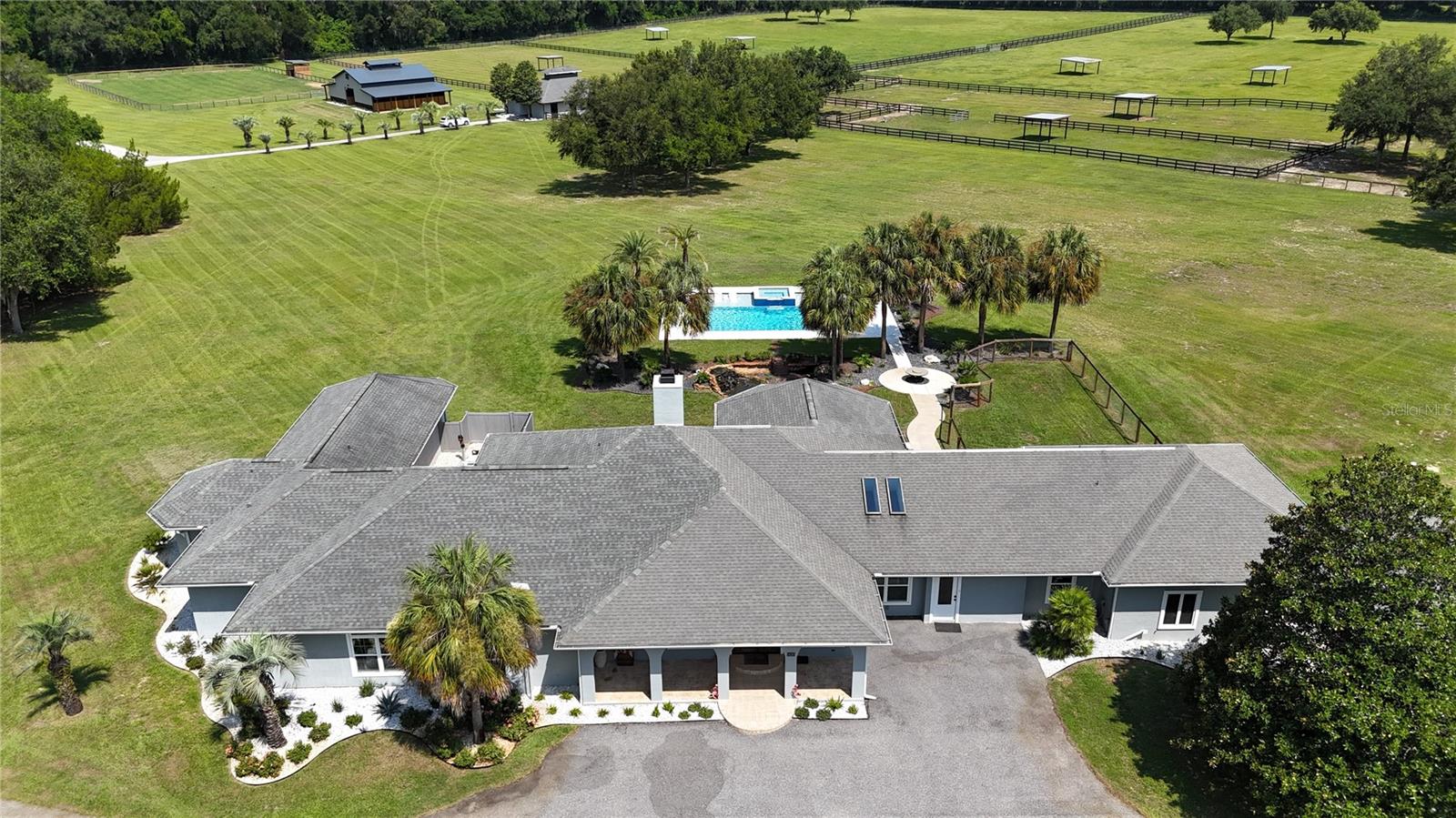 Resort Style Living. Premier Equestrian Facilities. Unmatched Privacy.
Where refined country living meets world-class equestrian amenities, this extraordinary 42.83-acre estate offers an exceptional opportunity to own one of Ocala’s premier horse properties. Less than 30 minutes from the World Equestrian Center, this beautifully improved estate combines luxurious living, state-of-the-art equestrian facilities, and resort-style outdoor living in one breathtaking setting.
Beautifully maintained with lush green pastures, mature shade trees, board fencing, fenced paddocks, and multiple run-in shelters, the farm provides an ideal setting for horses while offering picturesque views in every direction. 
The main house features 4 bedrooms and 4.5 baths, providing ample space and luxury for residents and guests.   The guest house offers an additional 3 bedrooms and 2 baths, perfect for accommodating visitors or extended family. 
The spacious main residence underwent an extensive renovation and expansion in 2021, including the addition of approximately 1,800 square feet. Improvements include a new owner’s suite and luxurious bath, a second owner’s suite complete with dual walk-in closets, separate vanities, elegant lighting, abundant storage, and spa-inspired baths designed for comfort and relaxation.  The gourmet kitchen, new roof, HVAC system, windows, and numerous interior upgrades. Filled with natural light, the home welcomes you with a stunning double-door entry, soaring ceilings, an impressive brick fireplace, and a beautifully designed island kitchen featuring stone countertops, custom wood cabinetry, and premium finishes throughout.
Step outside to your own private resort, where a spectacular newly constructed pool and spa overlook the rolling pastures and beautifully manicured grounds. With expansive lounging areas and breathtaking views of the farm, this outdoor oasis creates the perfect setting for entertaining family and friends or simply enjoying peaceful Florida sunsets.
This combination enhances the property's appeal, making it a versatile option for those looking to enjoy both elegant living and equestrian facilities.
Equestrian facilities are equally impressive. The newly constructed 16-stall center-aisle barn offers exceptional craftsmanship, spacious stalls, wide aisles, excellent ventilation, wash areas, and a professional layout suitable for private or commercial equestrian operations. Additionally, a secondary barn provides 4 stalls along with a new fly misting system, feed and tack room, plus a half bath for added convenience. Multiple fenced paddocks provide generous turnout, while covered equipment storage offers ample room for tractors, trailers, farm implements, and additional equipment.
Adding even more versatility is an approximately 1,800-square-foot guest house featuring three bedrooms, two bathrooms, and an attached two-car garage—ideal for guests, extended family, caretakers, or rental opportunities. There is a storage room currently used as a bunny house, but it could be repurposed for your choice of use.
Whether you’re an equestrian professional, trainer, breeder, or simply searching for a private luxury estate in the heart of Ocala’s horse country, this extraordinary property offers an unmatched combination of refined living, first-class equestrian amenities, and an unbeatable location.