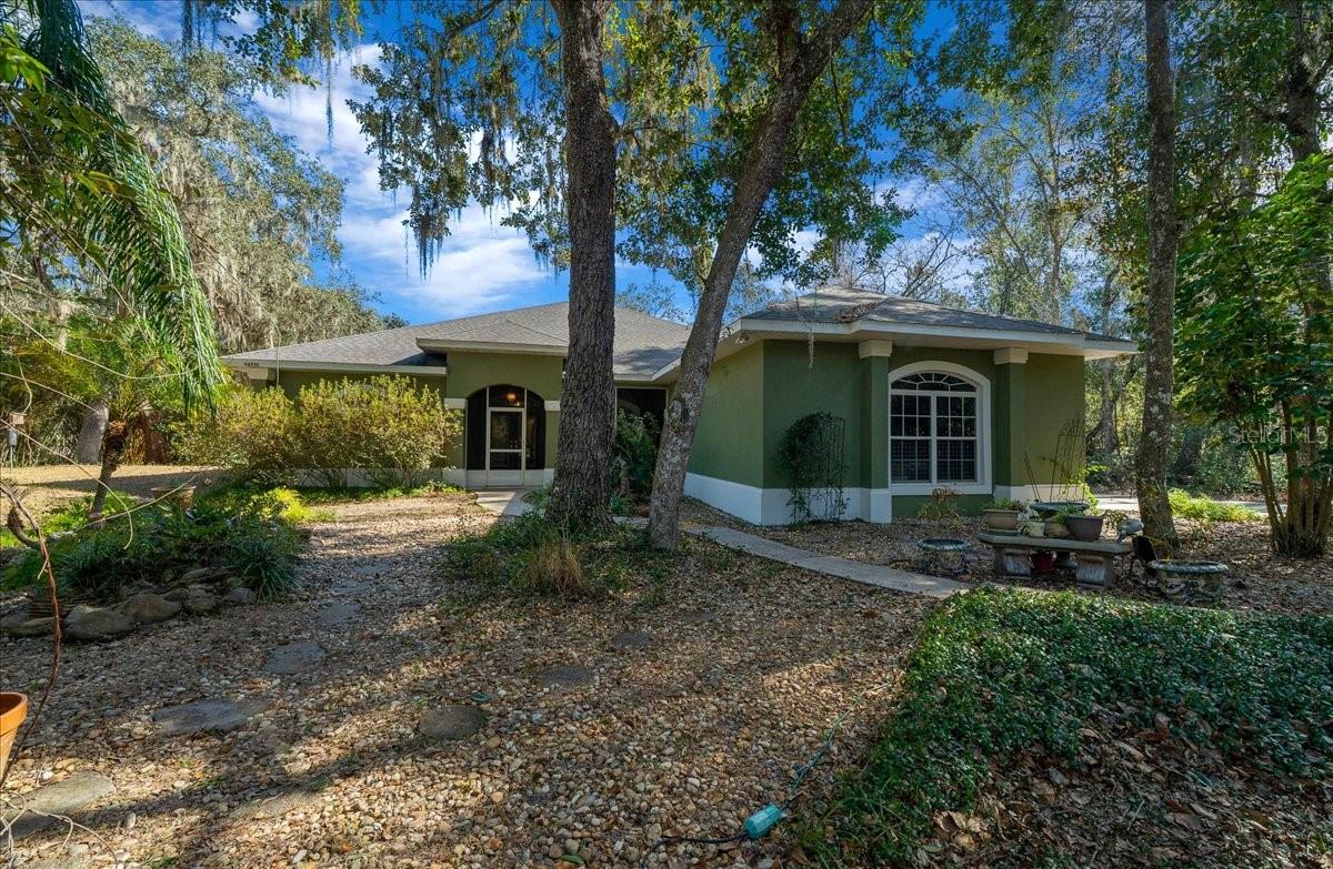 Live the Florida dream in this gorgeous 3 bedroom, 2 bath pool home on 2.83 acres of peaceful, agricultural zoned land, perfectly situated on a quiet dead end road. With 2,288 sq. ft. of spacious living, this property offers a private oasis with waterfront canal access and the unique opportunity to enjoy all that Florida’s beautiful Chain of Lakes has to offer. Whether you love boating, kayaking, or simply relaxing by the water, this home has it all. Step through the front screened in porch and into the dining area that flows seamlessly into the living room, highlighted by a cozy wood burning fireplace, natural light throughout and custom built in shelving. The large kitchen is a chef’s delight, featuring abundant cabinet and counter space, a functional layout, pantry and an additional eating area for casual meals or morning coffee overlooking your serene surroundings. Oversized primary suite creates a true private retreat, complete with a cozy seating area and a spacious walk in closet. En suite bathroom features dual vanities, a walk in tiled shower, and an soaking tub, an ideal place to unwind after a long day. The split floor plan ensures privacy for guests, with two additional bedrooms and a guest bathroom located on the opposite side of the home. One of the home’s standout features is the large, covered, screened in pool area, complete with a solar heated pool, spa, and views of the canal and property. The property also includes a Koi pond, adding charm and serenity, and plenty of space to build a barn, garage or additional outbuildings to suit your lifestyle. For water enthusiasts, the canal provides direct access to the Chain of Lakes, making it easy to launch a boat, kayak, or canoe and explore miles of scenic waterways. The home has been well maintained with a New roof and HVAC system installed in 2020, Pool resurfaced in 2019 and even comes with a 1 year home warranty at closing for added peace of mind. Despite its private, tranquil setting, the home is conveniently located near The Villages, offering quick access to shopping, restaurants, entertainment, and hospitals. This home truly offers a rare combination of privacy, functionality, and Florida waterfront lifestyle. From relaxing in your solar heated pool and spa, to exploring the canal, to simply enjoying the spacious grounds and natural beauty, this property is a dream come true for anyone looking to embrace the best of Florida living!