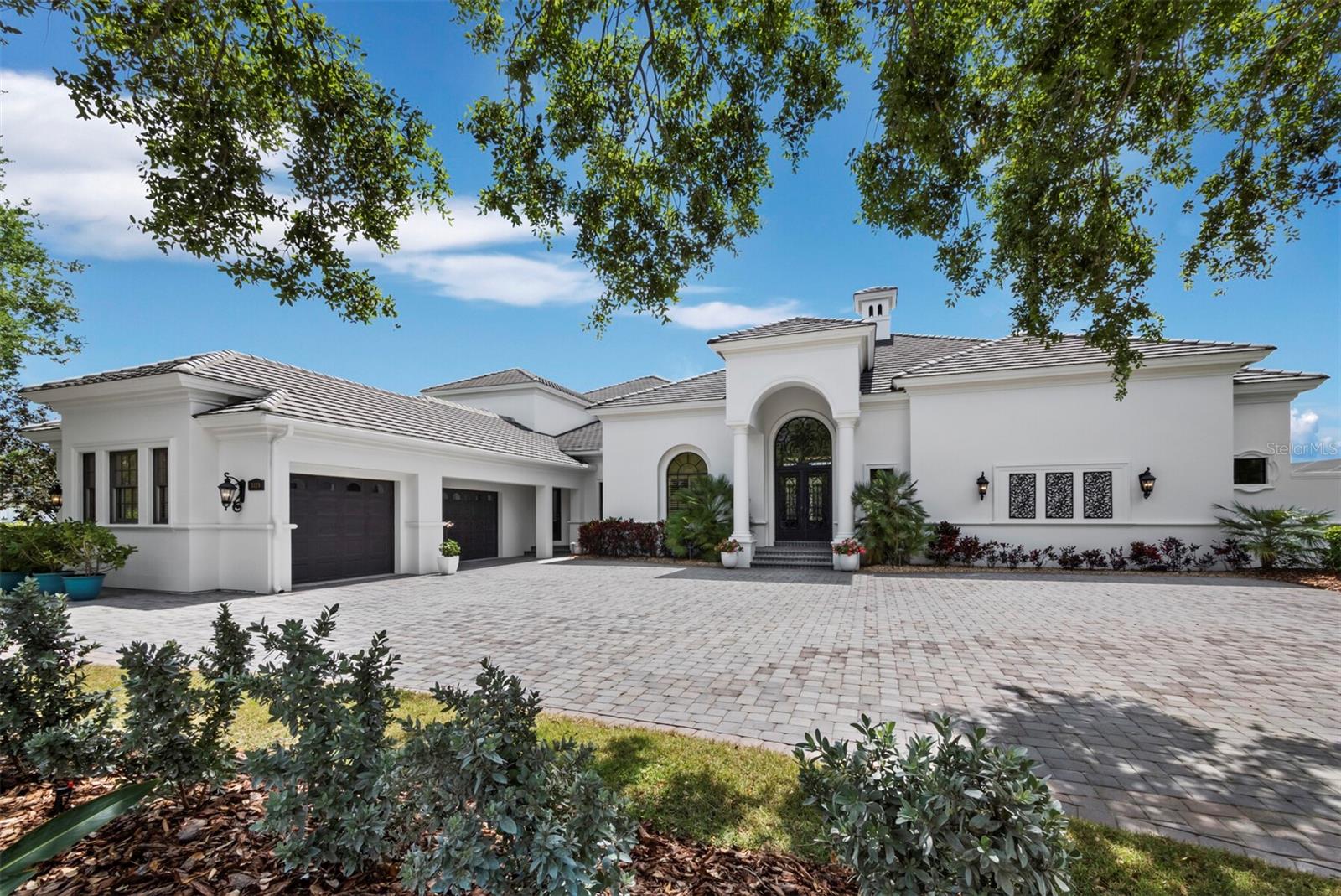 Set along the 11th green within the private, guard-gated Founders Club, this custom residence by John Cannon Homes captures sweeping views of the golf course, lake, and preserve across a beautifully positioned 0.69-acre homesite. Spanning over 5,700 square feet, the two-level design is both elegant and highly livable, with soaring ceilings, detailed millwork, and a natural flow that supports both everyday comfort and large-scale entertaining. A gracious foyer introduces formal living and dining spaces, while the heart of the home opens to a spacious family room and chef’s kitchen featuring premium appliances, a Wolf gas cooktop, oversized island, walk-in pantry, and a sunlit breakfast area framed by aquarium glass overlooking the water and fairways. Walls of French doors create a seamless transition to the expansive screened lanai, where the pool and spa, outdoor kitchen, and covered living areas are surrounded by tranquil views, an ideal setting for quiet mornings or evening gatherings. The primary suite is thoughtfully designed as a private retreat, complete with a sitting area, custom office, dual boutique-style closets, and a spa-inspired bath with a hydrotherapy tub, oversized shower, and dual water closets. Two additional guest suites are positioned in a separate wing for privacy. Upstairs, accessible by elevator or stairs, is a generous bonus room with a wet bar, fireplace, and a full bath that opens to a terrace with long, open views across the course, easily adaptable as a fourth bedroom or private guest quarters. Additional highlights include a wine cellar, butler’s pantry, travertine and hickory flooring, coffered ceilings, impact-rated openings, and an oversized three-car plus garage. The Founders Club spans 700 acres of preserved natural beauty, offering a refined yet relaxed lifestyle with optional membership to its Robert Trent Jones Jr.-designed championship golf course, clubhouse, dining, fitness center, and tennis and pickleball amenities. This home is defined by its scale, setting, and architectural integrity, and is positioned within one of Sarasota’s most established private communities.