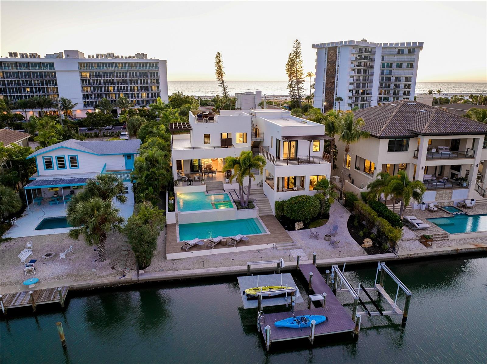 Under contract-accepting backup offers. In a world where more is usually never enough……. 161 S. Polk Drive is JUST ENOUGH and MORE OF EVERYTHING YOUR DREAMS ARE MADE OF!   Positioned waterfront between St. Armands Circle and Lido Beach, you can start your day walking just one block to put your toes in the sand and soak up the morning sun and then head straight to your favorite lunch spot on the circle.  Upon returning home, take up lounging in the split-level, salt water pool and relax to the sounds of the water as it crests the infinity edge OR you can choose one of the many decks, from rooftop on down, canal to Gulf, to savor the sun, the breeze, the views and the peacefulness all around you.  Once evening arrives, hop on the boat for a pleasant ride to your waterfront dining of choice or enjoy a glass of wine as you unwind with soothing music, the gentle movement of the water and savor the setting sun.  This privately gated, coastal contemporary home encompasses over 4,600 square feet of interior living space with an open plan from living to dining to kitchen and on to the outdoor patio with a full wall of pocketing sliders.  The acacia wood floor will be the first to grab your eye, but you will then be drawn to the unlimited other features of this home.  From the many windows offering abundant natural light, to the built-ins, wet bars, oversized kitchen island, 3 en-suite bedrooms all with private balconies (includes first and 2nd floor owner suites), elevator, outdoors showers, sauna, ‘hidden’ oversized laundry room with 2 sets of washers and dryers, oversized boat dock with 2 lifts……. Shall I go on??  The well thought out configuration of this home rationalizes JUST ENOUGH of comfortably elegant entertaining mixed with intimate peace and privacy.  Recent improvements include A/C handlers and compressors, tankless water heater and pump, flat tile roof decking, refinished exterior wood railings, pool pumps and actuators, in-ground drainage system, refreshed landscaping, exterior pressure washing, recent elevator service completed