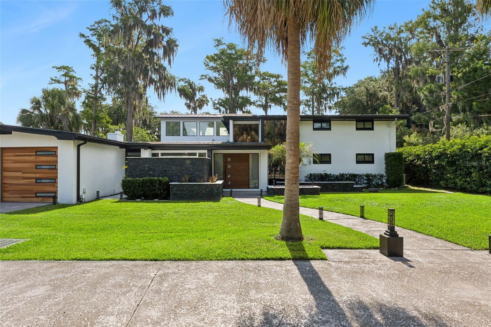 Welcome to your new dream home! Experience the rare blend of luxury, privacy, and lakefront living with this extraordinary pool home on Lake Jessamine, situated on 2.67 acres with NO HOA. Tucked away on a cul-de-sac behind a gated entry, this remarkable property offers the feeling of a private retreat while still placing you in the heart of Orlando. A long driveway and manicured landscaping create a stunning first impression as you arrive. A spacious two-car garage awaits at the end of the driveway, as well as an in-law suite complete with a kitchenette, to provide the perfect setup for guests or older relatives. Beyond the entry, the home immediately welcomes you with soaring ceilings, dramatic windows flooding the space with natural light, and elegant finishes throughout. A striking accent wall in the foyer sets the tone, while a peaceful koi pond and sanctuary area create the perfect setting for quiet mornings and tranquil reflection. The cozy living room centers around a beautiful fireplace, creating a warm atmosphere for evenings spent with loved ones. Remodeled in 2019 and with new plumbing in 2026, the kitchen is truly the heart of the home and a dream for any culinary enthusiast. Thoughtfully designed with a wraparound breakfast bar, oversized island, crown-molded cabinetry, subway tile backsplash, and top-of-the-line appliances, every detail was curated for both beauty and functionality. A gas range with custom hood and pot filler, spacious walk-in pantry, and abundant storage make entertaining and every day living feel equally effortless. Just behind the kitchen, a wine storage wall adds a elevated design feature perfect for showcasing your collection.The primary suite, located on the first floor, provides private access to the outdoor living area and a spacious walk-in closet with custom storage(2026) and plantation shutters that create the perfect setting to get ready for the day in. The en suite bathroom features a gorgeous freestanding tub, oversized walk-in shower with rain shower head, and a dual sink vanity. Upstairs, a breathtaking floating staircase with floor-to-ceiling windows leads to additional bedrooms and a home office space, ideal for remote work or creative pursuits. Additional bedrooms provide plenty of storage, natural light, and space so everyone in the family can feel at home. Step outside and discover your own private lakeside paradise! The resort-style pool and spa overlook Lake Jessamine, creating an unforgettable backdrop that you'll never grow tired of. A covered patio provides the perfect setting for al fresco dining, while the fenced backyard offers room for four-legged friends and play. Head out onto the lake from your private dock and covered boat lift for endless days on the water. Recent upgrades provide peace of mind, including a new roof in 2019, new exterior & interior paint in 2026, updated electrical and plumbing systems in 2026, and a recently upgraded seawall. Just minutes from I-4, you’ll have quick access to downtown, Orlando International Airport, theme parks, and world-class shopping and dining destinations including Mall at Millenia, Florida Mall, and Costco. This property is more than a home, it’s a private lakefront estate offering luxury, convenience, and the ultimate Florida lifestyle all in one extraordinary setting. Don't miss out on this amazing, well cared for home in an ideal location, schedule your private showing TODAY!!!