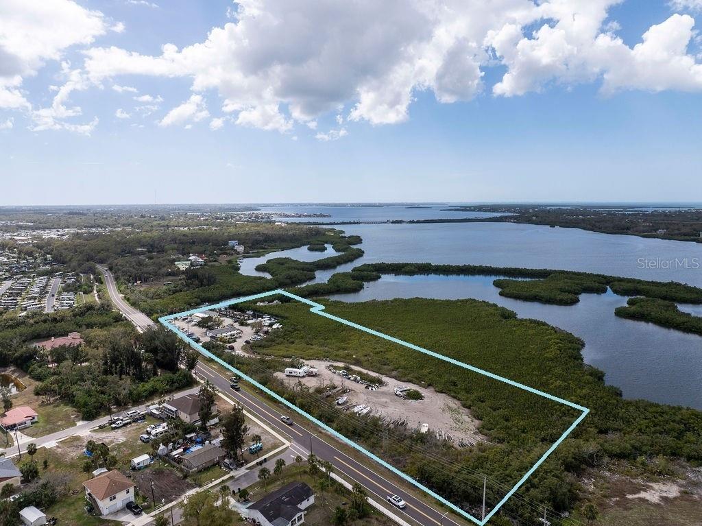 Palm View Marina presents a rare waterfront redevelopment opportunity at 6817 Bayshore Road in Palmetto, Florida, directly on the north shoreline of McMullen Creek at its confluence with the Manatee River watershed, offering immediate navigable access to Terra Ceia Bay, Tampa Bay, and the Gulf of America. The property features direct waterfront access with 25 +/- boat slips, covered lifts, and an established dock system. Positioned along the historic Old Tamiami Trail (Bayshore Road) just east of U.S. Route 41, the site is zoned PD-W (Planned Development Waterfront) and VIL (Village), offering flexibility for marina expansion, mixed-use redevelopment, residential, hospitality, or marine support uses, subject to county approvals. Submerged lands are owned, further enhancing development and income potential. A notable advantage exists along the Old Tamiami Trail corridor, where extending the existing roadbed and utilizing dredge spoils are most likely feasible.