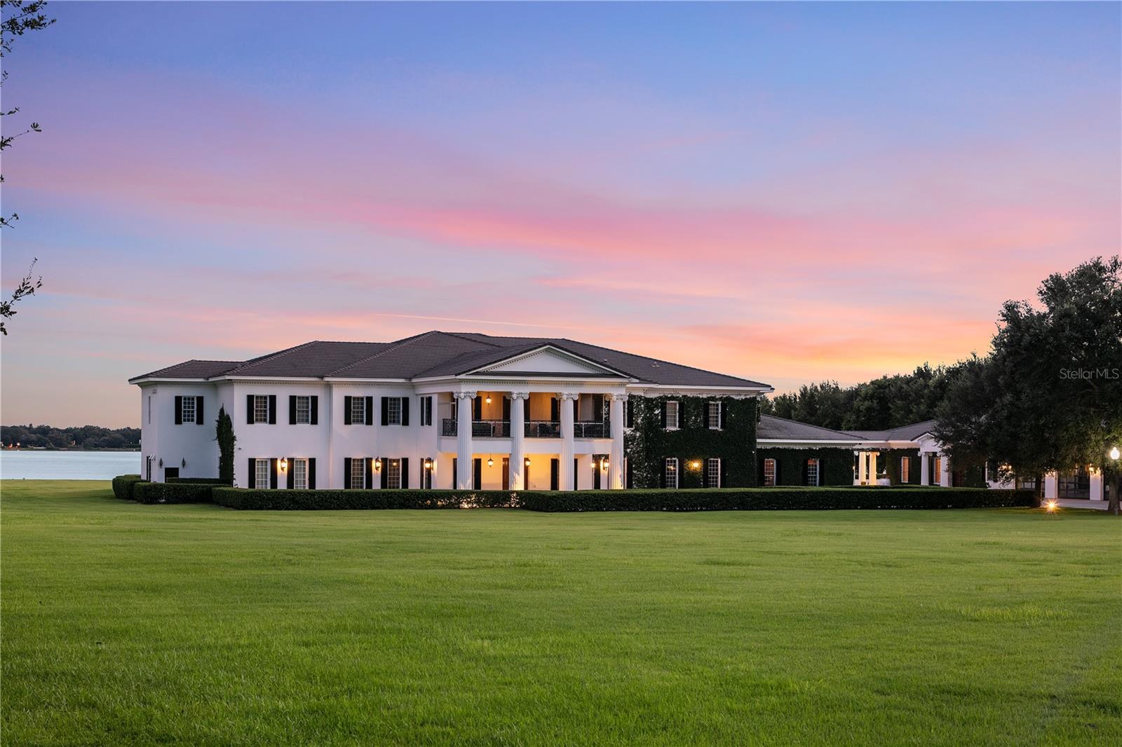 Showcasing Central Florida’s most iconic lakefront estate: an 18-acre compound with 614 feet of pristine frontage on Lake Down on The Butler Chain of Lakes. The Windy Ridge Estate is comprised of multiple buildings spanning 51,000 square feet of space including an expansive 20,333 square-foot Georgian-style Plantation mansion that is a showplace residence with generous luxurious spaces, classic elegance, and the ultimate in security and serenity. The walled entry opens to a grand foyer with a floating mahogany staircase, marble floors, paneled walls, and Murano chandeliers. An art gallery leads to a spacious living room featuring rich mahogany millwork and expansive lake vistas. Gourmet kitchen: salamander, dual double convection ovens, commercial icemaker, full-size refrigerator, and freezer. The main level includes one of two owners' suites, plus a library-lounge or a possible sixth bedroom. Dual staircases or a Thyssenkrupp elevator provide access to the upper level, which features four-bedroom suites, including the primary retreat. An 85-foot parlor with 20-foot ceilings, built-in bookshelves, and a wet bar provide a dramatic entertaining space. Screened porch captures southern lake views and Disney fireworks. Breezeway connects to a 5,600 SF rustic lodge with a bar, catering kitchen, entertainment hall, and locker facilities. Outdoor amenities: Junior Olympic pool, spa, decorative fountain, architectural lighting, direct lake access. The vast and open water location offers an ideal space for seaplane arrivals and departures. Additional structures include a 4,000 SF paneled garage with 20-foot ceilings, an office, and a guest apartment; a 3,800 SF storage building; three separate garages accommodating motor coach and car collection; and staff quarters with a private courtyard. A rare fusion of Southern grandeur, lakefront serenity, and equestrian potential—without any interference of an HOA.  Truly a legacy compound crafted for those who demand the extraordinary.
