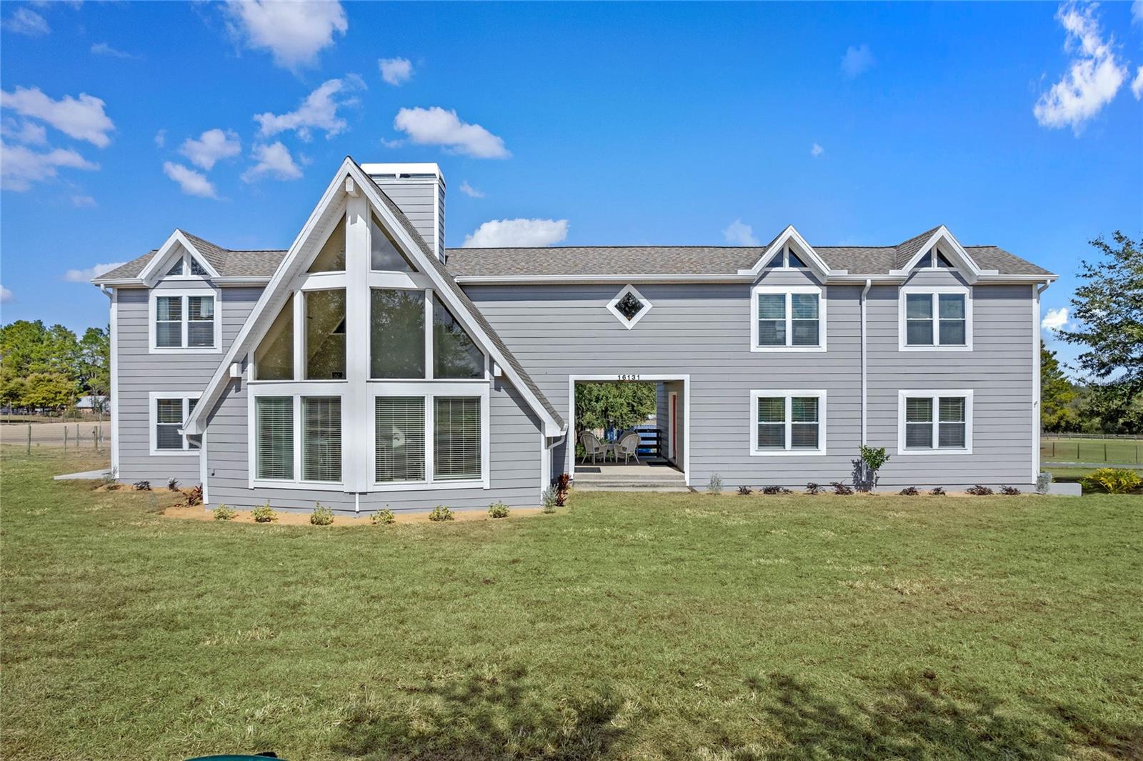 Located at the quiet end of Johns Lake Road, enjoy COUNTRY living roughly 5 MINUTES from SHOPPING & RESTAURANTS! This contemporary farmhouse offers a living room with a “wall of windows” reaching 22' high allowing tons of natural light to enter with a wood burning fireplace to keep you warm on those cold winter nights. There are 4 BEDROOMS with 4 BATHS, a cabinet filled kitchen, the lower cabinet shelves all pull out for ease of reach, with an abundance of countertop space incorporating a huge breakfast bar..The dining room is right around the corner allowing the smells of a fabulous meal to drift in, Yummy! There’s also a bedroom and full bath located on the first floor allowing privacy for guest. At the top of the staircase, you’ll find French doors that open to the massive owner's suite featuring an ensuite that includes dual sinks on the long vanity, a jetted tub, separate shower and walk in closet. From there, stroll down the spacious hallway past the upstairs OFFICE to find a TWO sizable bedrooms, another bathroom with dual sinks vanity, shower/tub combo and linen closet and a sitting room. The BREEZEWAY is a wonderful outside relaxation area located between the front door and a HUGE 768 square foot room above the garage with its own air conditioner, LOTS OF SUNLIGHT, a bath with a sizable shower which would make an amazing IN-LAWS SUITE, game room, family room, movie theater...the opportunities are endless. This (almost) 5 ACRES of peaceful horse property features two pastures and is completely FENCED with 2"X 4" non-climb horse fence and has an electric driveway gate offering a secure home for you and your critters. The back pasture includes a 4 stall center aisle barn that has stall fans and automatic waterers. In the front field you'll find TWO more stalls, one enclosed to confine your smaller animals/birds for protection from the elements. There's an air-conditioned storage building that needs attention but has been the feed and tack room for 25+ years and a shipping container that was modified for better air flow used for hay storage. Situated just after the stop sign on the quiet end of the road where neighbors still walk and ride bikes, your dream home awaits.