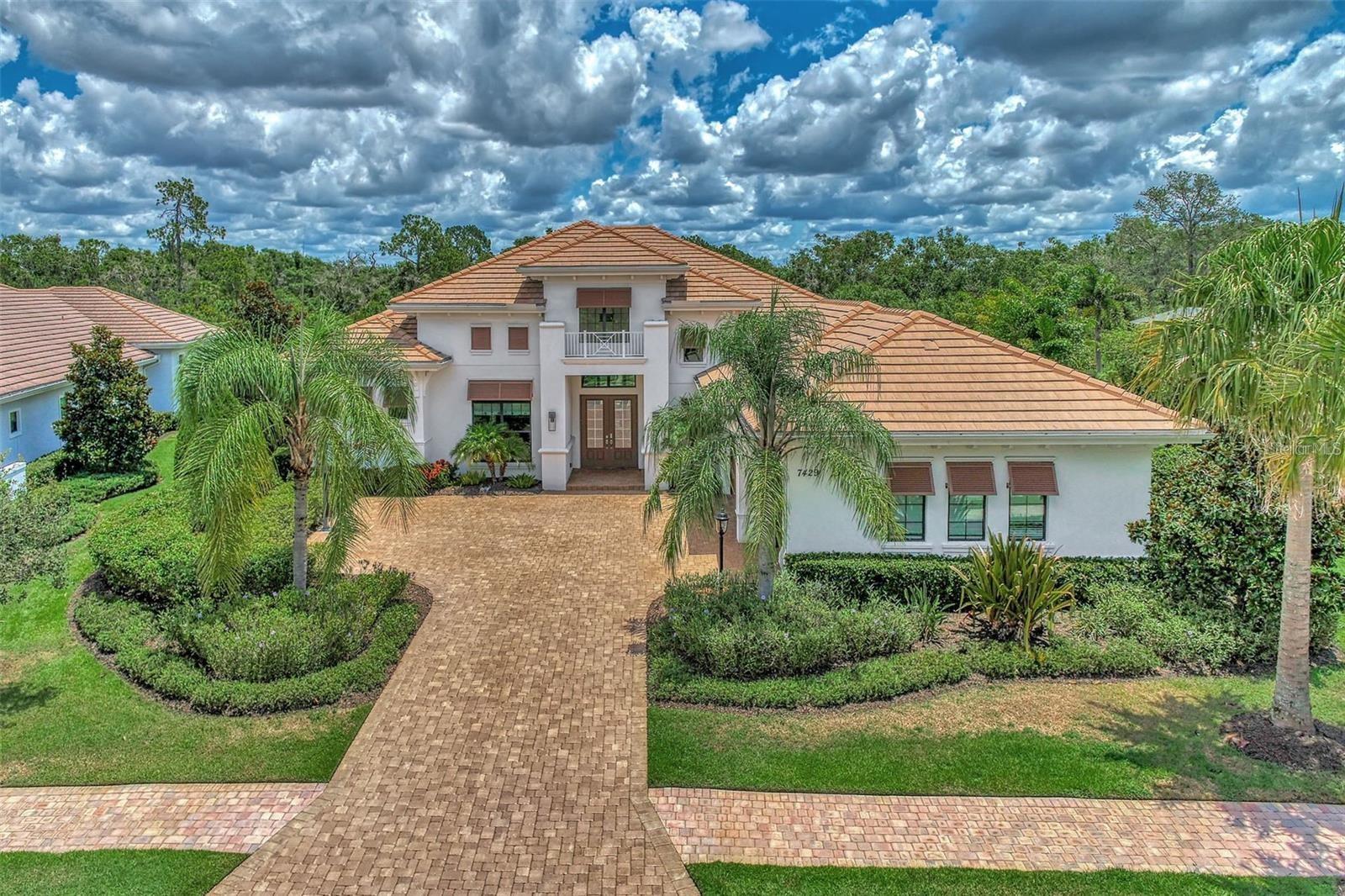 Located in the highly sought after gated community of Country Club East, this modern and stylish residence offers the perfect blend of comfort and sophistication. The former Gardenia II model by Stock Homes backs up to a picturesque preserve offering a serene and private setting. The thoughtfully designed open concept kitchen, living room and dining area, with soaring 14 foot ceilings and ceramic tile flooring throughout, is ideal for entertaining family and friends. Grandeur and elegance abound the main living space of the home. The great room features endless upgrades, including crown molding, double coffered ceilings, designer lighting, custom window treatments and a built-in wall feature. Your eye will be instantly drawn to the custom built 90-bottle glass-enclosed wine wall in the dining space. The gourmet kitchen features a massive 7’ x 10’ island, quartz countertops, gas cooktop, ample cabinet space and a walk-in pantry. Sliding pocket doors span the back of the home, adding abundant natural light to the living space and creating a seamless transition between indoor comfort and outdoor serenity. The master suite is a retreat unto itself, offering a private alcove entry, two walk-in custom closets, a spacious bedroom and sitting area with glass French doors open to the oversized screened lanai. A sweeping hallway leads you to the spa-like luxury master bathroom featuring an oversized (4.5’ x 10.5’) walk-in shower with floor to ceiling tile, two separate vanities, a free-standing soaking tub and a linen closet. Three guest bedrooms are en-suites with expansive closets, providing comfort and privacy for family and visitors. The well-appointed, stylish office, which features a soaring 12-foot custom wooden coffered ceiling, motorized blinds with custom window treatment and French doors, caters to your work-from-home needs. Just when you think you’ve seen it all, stroll down the rear hallway to a hidden oasis. The versatile, oversized family room, which features pocket sliding doors to the lanai, tray ceiling, custom drapery and motorized blinds, embodies a cozy feel perfect for a weekend movie night or just snuggling up with a good book. Freeform pool featuring sun shelf, integrated spa and two gas fire bowls with a waterfall feature. The granite topped outdoor kitchen with large island outdoor, equipped with a built-in gas grill, sink and beverage refrigerator. Enjoy a night of evening fun with integrated lighting and bistro lights in the back area, perfect for a family cornhole tournament. Additional features include laundry room that is functional with tons of cabinet space, sink, water softener and water filtration systems, hurricane impact glass throughout. State-of-the-art smart home technology including two smart thermostats, smart entry lock, home security and camera system which can all be remotely controlled. Located a short distance to the neighborhood clubhouse which includes a community room, the newly appointed gym and the largest of three community swimming pools. The neighborhood is also home to several of Lakewood Ranch Country Club’s facilities, including one of its 4 golf courses, a driving range, clubhouse restaurant and pickleball courts. Club membership has availability for a limited time following its recent 3-year waitlist. This home is centrally located and a short drive to University Town Center shops and restaurants also, nationally ranked beaches and A rated public schools.