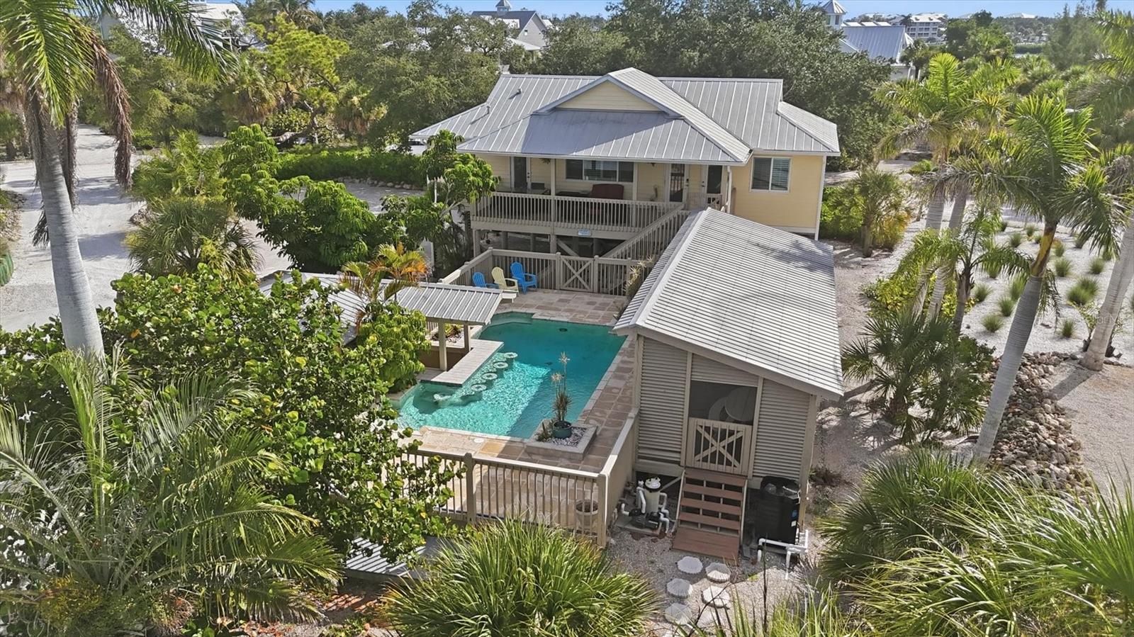 Experience the ultimate Don Pedro Island waterfront lifestyle in this beautifully updated Key West-style home, perfectly positioned on nearly a half-acre in one of Southwest Florida's most desirable barrier island communities. Offering 2 spacious primary suites, 2.5 baths, and exceptional indoor-outdoor living, this move-in ready island retreat is ideal as a full-time residence, vacation home, or income-producing rental.

Inside, you'll find a bright coastal interior featuring wood-look tile flooring, high coffered ceilings, impact-rated windows and doors, plantation shutters, granite countertops throughout, stainless steel appliances, and quality finishes at every turn. An air-conditioned bonus room with a half bath provides flexible space for a home office, guest overflow, fitness room, or game room.

Designed for entertaining, the outdoor living space is truly spectacular. Relax in the resort-style pool featuring a swim-up bar with seating for six, host unforgettable gatherings in the covered outdoor kitchen and grilling area, or unwind beneath the expansive 12' x 36' covered lounge with metal roofing, composite decking, and louvered privacy walls. Additional features include an outdoor shower, golf cart garage/workshop, covered boat and vehicle parking.  Boaters will love the shared dock and private boat ramp on Kettle Harbor, providing direct, no-bridge access to the Intracoastal Waterway and the Gulf of America. Spend your days fishing, boating, shelling, or exploring nearby Palm Island, Boca Grande, Stump Pass, and the pristine Gulf beaches, then return home to breathtaking sunset views over Kettle Harbor.