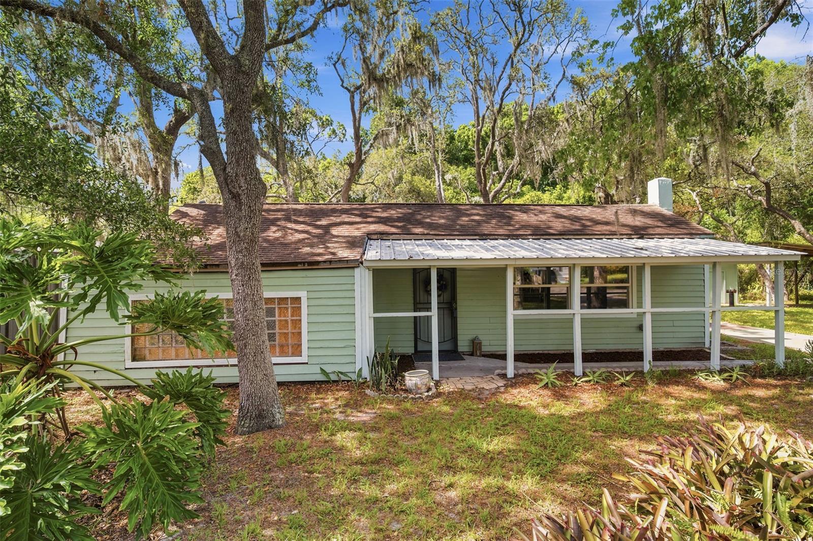 WELCOME TO YOUR COUNTRY RETREAT at 12307 Eagle Lake Ave, New Port Richey, FL in Pasco County. This is a UNIQUE PROPERTY where the adjacent parcel is included in the sale. 12307 Eagle Lake Ave with TAX ID: 09-25-17-0040-04800-0170 sits on lots 17 & 18 (8991 sqft lot size) & 0 Eagle Lake Ave with TAX ID: 09-25-17-0040-04800-0190 sits on lots 19-20-21 (11,662 sqft lot size) for a total of 5 lots with 2 legal descriptions & just under 1/2 acre combined!!! Your updated single family home features 2 bedrooms, 1.5 bathrooms as well as 2 covered patio areas, 3 separate sheds/workshops, outdoor firepit & pergola/carport parking. This OVERSIZED parcel is located in Moon Lake Estates where there is NO HOA, NO CDD & not in a flood zone. Enjoy PRIVACY GALORE in this rural, wooded setting & fenced along the left side. As you step inside, you'll LOVE the FRESH interior paint in a warm neutral color & NEW floors elegantly dressed in luxury vinyl (no carpet anywhere!). SUNSHINE streams inside through the multiple windows illuminating the interior together with the BRIGHT light fixtures. The OPEN FLOOR PLAN consists of the kitchen, living & dining rooms. The REMODELED eat-in kitchen features expansive laminate counters, beadboard backsplash, double stainless steel sink, crisp white shaker-style cabinets with knobs, LED flush lights, WALK-IN PANTRY with RECLAIMED SHIPLAP on the walls & ceiling & newer appliances including a side-by-side fridge, microwave & GAS range serviced by propane (permitted). The wood tall pantry cabinet will convey with the sale. Create memories during mealtime in the dining area & then relax in SPACIOUS living room with a ceiling fan. The home is heated with a PHENOMENAL wood burning fireplace featuring built-in shelving, wood mantle & a stone hearth. The primary bedroom has DUAL CLOSETS & private en-suite. This private half-bathroom has a cabinet vanity with sink & water-saver toilet. As this bathroom is quite LARGE, the future owner can install a shower here and inside laundry hookups as the laundry is currently in the outdoor shed. In this split bedroom plan, the remaining bedroom is found on the opposite wing of the home. Both bedrooms can fit king-size furniture. The 2nd bedroom has a GIGANTIC WALK-IN room with 2 sets of 3x4 window blocks, wooden ledge as chair rail & beadboard wall accents. This room can EASILY be utilized as the office/den. This RENOVATED main bathroom features a SLEEK WHIRLPOOL/SPA BATH TUB, nice vanity with cultured marble counter, newer toilet & built-in shelves. Need space to tinker? NO PROBLEM! There is a LOT OF LAND to design you DREAM OUTDOOR OASIS! GORGEOUS GRANDFATHER OAK TREES reside on the property along with MATURE plants including TROPICAL bromeliads, amaryllis, aloe & Staghorn air plant. This property is serviced by 3 built-in AC units located in both bedrooms & the kitchen, private well & septic. Want to raise chickens? This property is IDEAL for chickens & your furry friends. As 2 parcels of land (5 total lots) are included, you can build a home on the adjacent lots for multi-generational living or investment! Location is AMAZING near schools, beaches, medical plazas, shopping centers, restaurants, places of worship, airport & tourist attractions. MAKE THIS YOUR FUTURE HOME!