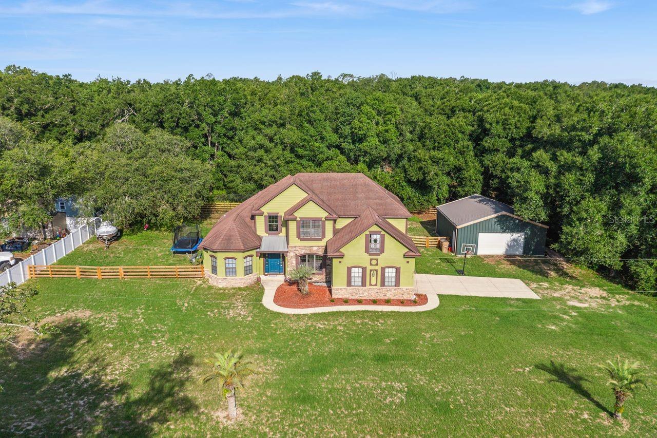 Welcome to this spacious 5-bedroom, 3-bathroom home situated on a generous 1.68-acre lot in the desirable Michigan Acres subdivision. The first floor features a convenient layout with the primary bedroom, a secondary bedroom, living room, dining room, and kitchen, offering comfortable everyday living and excellent functionality. Upstairs, you’ll find three additional bedrooms and a full bathroom, providing ample space for family, guests, or flexible use. Enjoy peaceful outdoor living on the large, covered patio overlooking the conservation area, with no rear neighbors for added privacy. The fully fenced-in backyard is ideal for pets, play, or future outdoor enhancements. This property includes an attached 2-car side-entry garage plus a rare bonus: a detached 900 sq. ft. steel garage building, perfect for additional parking, storage, workshop space, or hobby use. Located in a NO HOA community and just 15 minutes from Mount Dora and Downtown Eustis, this home offers both space and convenience in a quiet, natural setting.