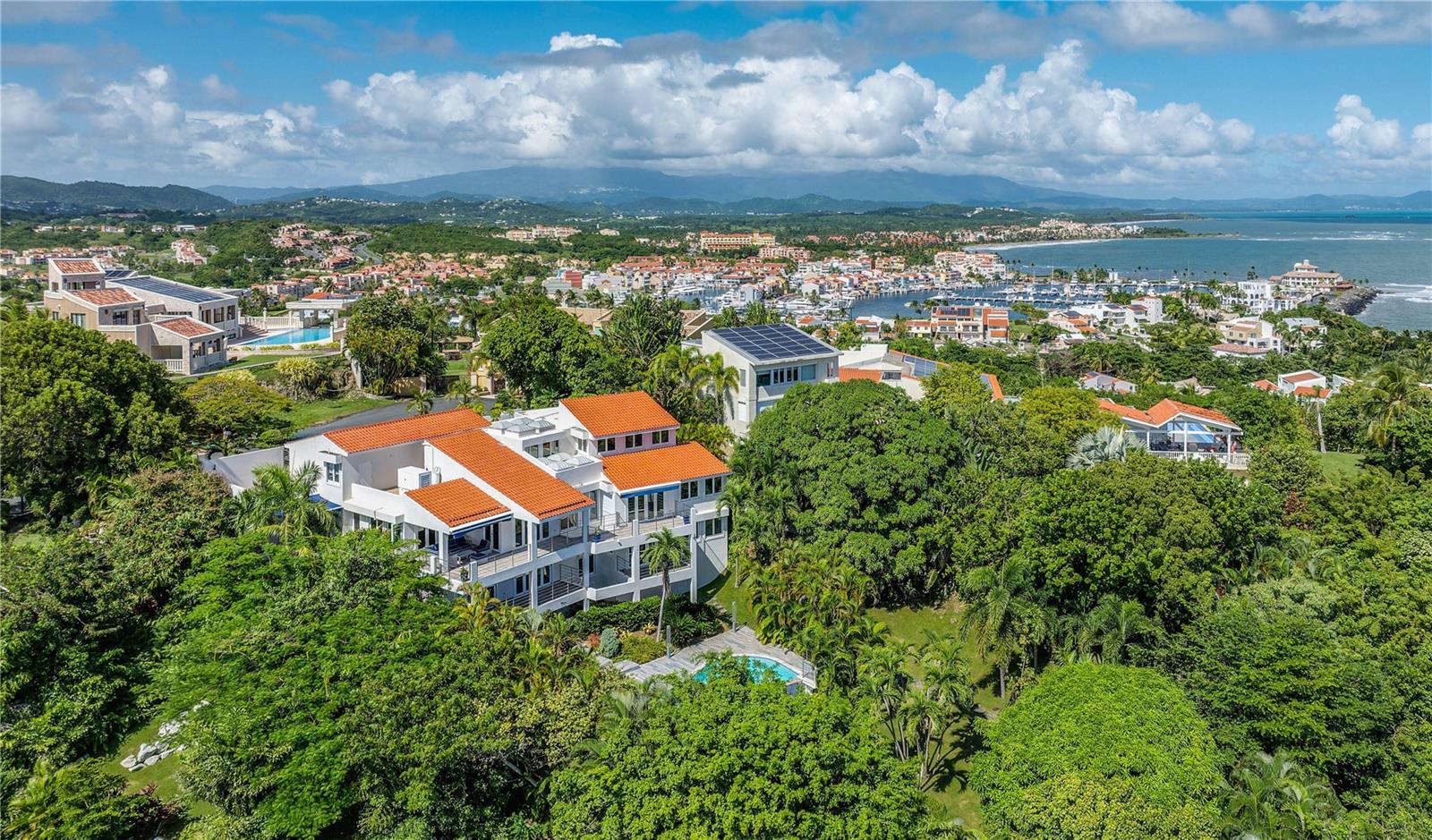 ***SOLD*** Nothing short of spectacular vistas from high above the sea side cliffs of Ridge Top Road in Palmas Del Mar, at 12 Ridge Top. This slopeside estate offers 5 bedrooms, 5 full bathrooms with 2 half baths, in a custom-designed 3 story layout complete with elevator floor to rooftop. With just over 5,116 interior sq.ft of air-conditioned living and approx. 2,413 sq.ft of exterior living, this gated suburban country estate satiates the desire for both view and space. Boasting a contemporary aesthetic illuminated by warm natural light throughout, the 23’ in ceilings highlight the uniquely private nature of this highly coveted street. Serving as the perfect space for entertaining, the entry level features an oversized sitting room, powder room and guest suite, retrofitted with its own private wet bar and kitchen. On the ground floor, double sized open areas serve as combined living and dining, seamlessly connecting to the gourmet eat-in kitchen and covered terraces, affording 180 degree scenic vistas from different vantage points. 2 bedrooms, of which one offers a suite bath, and 2 powder rooms, round out this level's offerings. Affording the utmost in serenity with an indoor garden and water feature, the second floor showcases a wine cellar, laundry, ensuite guest bedroom with covered balcony, and the primary suite with walk-in closet and a spa-inspired bathroom with a terrace/outdoor shower. Outside, embrace the sun with your own private oasis. The covered patio with full bath and storage space leads out to the sizable pool, adorned by surrounding tropical foliage set on half an acre of land. A 3-car garage with approx. 619 Sq. Ft.  rounds out this exceptional home. Palmas del Mar is internationally renowned for its Yacht Club & Marina, golf courses, tennis courts, equestrian center, school, restaurants, shopping venues and beachfront location on the southeast coast of the island. Only a 40-minute drive from San Juan, enjoy the effortless suburban living  of the Caribbean master planned oasis.