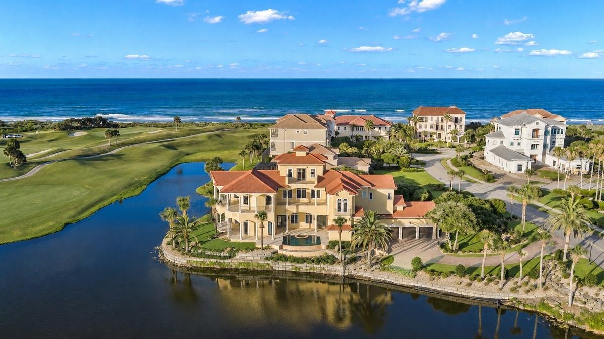 Located behind the exclusive North Gate of Hammock Dunes, this exceptional Mediterranean estate occupies one of the community's most coveted peninsula homesites. Perfectly positioned to capture panoramic views of the Atlantic Ocean, tranquil lake, championship golf course, and the ever-changing beauty of both sunrise and sunset, the residence spans more than 6,000 square feet across three beautifully crafted levels, blending timeless Mediterranean architecture with exceptional craftsmanship and relaxed coastal elegance.

Designed for both everyday living and gracious entertaining, the home offers generous living areas, a gracious formal dining room, chef's kitchen, spacious great room, private executive office, tiered home theater, oversized elevator, an inviting family room with a wet bar and dual wine refrigeration, well-appointed guest accommodations, and an oversized three-car garage.

Authentic Venetian plaster walls, quarter-sawn Bubinga (African Rosewood) flooring, imported Italian stone, custom millwork, solid bronze architectural railings, and soaring ceilings reflect an unwavering commitment to quality and craftsmanship.

The private owner's retreat overlooks the infinity-edge pool, tranquil lake, protected marsh, and the rolling fairways of the Tom Fazio Links Course, creating a peaceful sanctuary. The spa-inspired bath features dual dressing rooms, an oversized walk-through shower, a sculptural soaking tub, and views of the Atlantic Ocean.

Outdoor living is equally impressive. The infinity-edge pool overlooks the lake and the entire 7th hole of the Tom Fazio Links Course, offering the rare opportunity to watch golfers from the opening tee shot to the final putt with the Atlantic Ocean beyond. Covered lanais provide inviting spaces to enjoy quiet mornings and unforgettable sunsets, while a private beach walkover is just a short stroll away.

Constructed of concrete block under the stringent Dade County Building Code standards and meticulously maintained throughout ownership, the residence reflects exceptional pride of ownership. Recent improvements include a Wet Edge Signature Matrix Tahoe pool resurfacing (2024) and a new roof (2025), providing added confidence for the next owner.

Optional membership to the prestigious Hammock Dunes Club, recognized as a Distinguished Emerald Club of the World, offers two championship golf courses, exceptional dining, tennis, pickleball, croquet, bocce, a state-of-the-art fitness center, and an active year-round social calendar.

A rare opportunity to own one of Hammock Dunes' most distinguished residences, where timeless architecture, exceptional craftsmanship, and one of Florida's most captivating coastal settings come together.