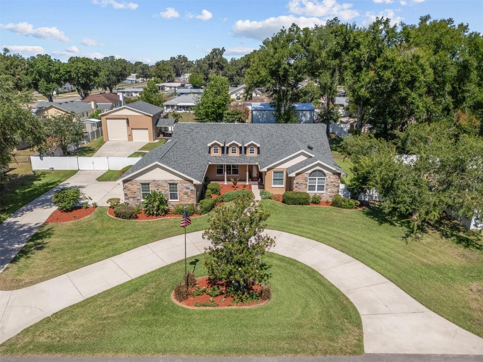 Welcome to this exceptional custom-built 5-bedroom, 2.5-bath pool home, with 32x30 detached garage, offering the perfect combination of luxury, functionality, and space both inside and out.Upon arrival, you’ll be impressed by the circular driveway, extensive parking areas, manicured landscaping, and attractive curb appeal highlighted by stone accents and a welcoming front porch. The property offers 0.70 acres making it ideal for large gatherings, multiple vehicles, boats, and RVs.Inside, the home features rich hardwood flooring throughout the main living areas, elegant crown molding, tray ceilings, plantation shutters, and a thoughtfully designed split-bedroom floor plan. The spacious living room features beautiful hardwood floors, a gas fireplace, plantation shutters, a wet bar with sink, and direct access to the pool area. The adjoining kitchen is designed to impress with custom wood cabinetry, granite countertops, stainless steel appliances, a gas range, dishwasher, refrigerator, double sinks, a large pantry, center island with additional prep sink, breakfast bar seating, and ample workspace for cooking.Adjacent to the kitchen, the breakfast area offers pool views and French doors leading directly to the screened lanai and pool area, seamlessly blending indoor and outdoor living.The private primary suite is generously sized and features plush carpeting, high ceilings, plantation shutters, and a spacious walk-in closet complete with custom built-in storage systems. The luxurious primary bath includes dual vanities with granite countertops, custom wood cabinetry, an oversized tiled walk-in shower with dual shower heads including a rain shower feature, built-in bench seating, and a private water closet.Three additional bedrooms feature plantation shutters and built-in closets, while the fifth bedroom is ideally situated near the laundry room and offers flexibility as a home office. A centrally located full bathroom includes dual sinks, tile flooring, and a tub/shower combination. A convenient half bath is located near the main living area for guests.Enjoy Florida living year-round in the screened swimming pool enclosure featuring a spacious pool deck and plenty of room for lounging and entertaining. The covered outdoor sitting area offers ceiling fans, electrical connections, slider windows, and comfortable space for outdoor gatherings.For those needing storage, workshop space, RV accommodations, or room for recreational equipment, the detached garage is a rare find. Constructed with solid concrete walls and electric service, the building features both a standard side-entry door and oversized roll-up doors measuring approximately 8’ x 9’ and 13’ x 11’, making it ideal for RV storage, boats, classic cars, equipment, or workshop use. RV hookups are already in place, adding even more convenience and versatility. The upstairs bonus room is the perfect game room, media room, or recreation space and includes a mini-split air conditioning system and pool table with furnishings that will convey with the sale.Additional features include a three-car attached garage with epoxy flooring, Generac whole-house generator, two HVAC systems, vinyl fencing, termite bait stations, multiple exterior electrical hookups, water spigots throughout the property, backyard irrigation, chicken coop, motion lighting, and approximately 62 feet of secured parking behind the fence. Home roof(2023), Detached garage(2022).