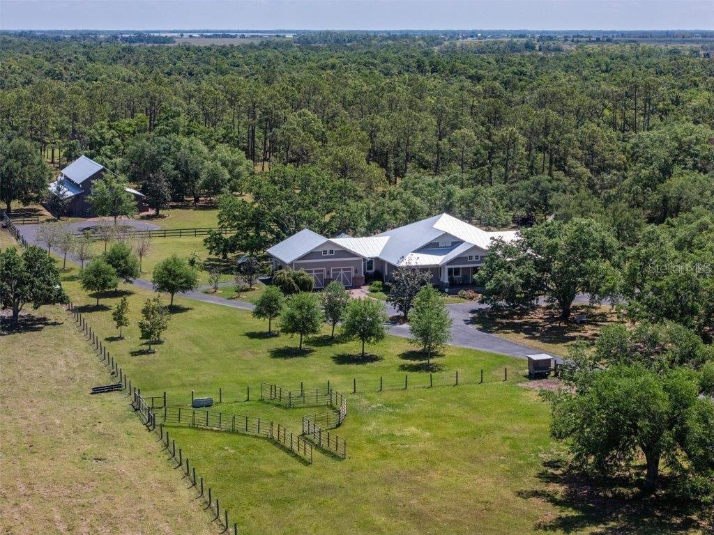 Welcome to a truly extraordinary opportunity along the scenic Myakka River. This private, fully fenced 51.4-acre estate offers an unmatched lifestyle, where every day feels like a retreat and the possibilities are as expansive as the land itself. Built in 2018, this custom 3-bedroom, 3.5-bath farmhouse seamlessly blends rustic charm with refined comfort, creating the ultimate sanctuary for those seeking space, serenity, and something truly special. Step inside to a warm, open-concept living space featuring rich wood floors, shiplap accents, and a cozy gas fireplace. The gourmet kitchen is a standout, equipped with a gas range with two ovens, quartz countertops, custom cabinetry and an expansive island ideal for cooking, gathering, and entertaining. The oversized walk-in pantry includes two additional built-in ovens and doubles as a laundry room, which opens into a mudroom that offers extra storage and everyday practicality. A separate office space provides a quiet place to work, create, or manage your homestead with ease. The spacious primary suite is a private retreat with a walk-in closet, a spa-inspired bathroom, and both indoor and outdoor showers for the ultimate Florida lifestyle. Two additional bedrooms include built-in closet systems. Large covered patios with roll-down bug screens create the perfect backdrop for relaxing evenings, outdoor dining, or watching the sunset in total comfort. The oversized two-car garage with golf cart parking also includes an air-conditioned loft space, ideal for a hobby room, home gym, or extra storage. Enjoy long term peace of mind with Anderson impact windows and doors, a brand new metal roof installed in March 2025, a whole house generator, and No flood insurance required. Known as Crooked River Ranch, the impressive 3,600 sq ft two-story barn  is a sought-after wedding venue and is now ready for your vision, whether as an equestrian facility, event space, or multi-use structure. It features two air-conditioned bathrooms on the main level, a 576 sq ft air-conditioned loft, and an attached 24x24 covered entertainment area. Just off to the side, a fire-pit gathering space with café lighting sets the stage for unforgettable evenings under the stars. The land is rich with opportunity,  cross-fenced pastures for horses, cows, chickens, or goats, a designated garden area, and endless room to roam. Explore your own private trail system, fish along the Myakka River, ride horses, hunt from your blind, or simply take in the abundant wildlife deer, turkey, wild hogs that roam freely through your property. Tucked away just 3.5 miles from Soleta Golf Club and directly across the river from the world-class TerraNova Equestrian Center, this estate offers unmatched seclusion without fees and convenience nearby. Whether you're envisioning a working ranch, family compound, luxury homestead, or a destination property like no other - this is your chance to own a piece of Myakka that simply can not be replicated.