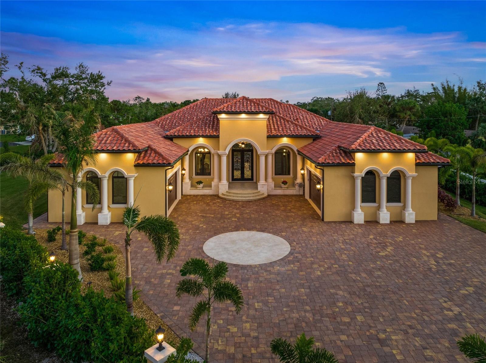 Be prepared to be captivated by this custom 2023 Spanish courtyard home. Every detail of this 4 bedroom 5 ½ bathroom SMART home, with two oversized garages has been thoughtfully crafted. Like a beacon in the storm this home stood the test of Mother Nature. Not just beautiful, but built to last with stem-wall construction, hurricane windows, steel hurricane doors and elevation. The gated property set back from the street with a long driveway adorned by Royal Palms. Enter double doors with custom wrought iron, over glass, accented with a half-circle transom window above for a dramatic light filtered entrance. The natural lighting of the front entrance illuminates the grand foyer with custom plaster walls and arch. Artist, Alex Sobolevsky of California has created a delightful coastal mural that extends from the interior walls of the foyer across the ceiling. A Spanish alabaster chandelier and sconce lights add elegance. The living room has soaring coffered ceilings, accented with custom plaster, LED lighting and the grandest of all, an imported Spanish alabaster chandelier. The floor to ceiling tile fireplace beckons attention, with rich wood cabinetry, glass shelving on custom plaster walls with subtle sparkles of gold. Beautiful tile floors with inlayed wood designs at the foyer and in the living room. The custom kitchen centerpiece is an impressive waterfall island of granite with metallic flecks. The brass chandeliers above pick up the romantic shade of metal in the granite. There is a bar glass, brush and a separate faucet for filtered water. Functional and beautiful subzero refrigerator-freezer, Samsung built in oven and microwave, and gas burner cooktop. There is a pot faucet over the cooktop and a faucet over the coffee bar. An addition to the chef’s dream is an amazing hidden 4’2”x 7’6” pantry. The eating area has impact aquarium windows with an unobstructed view of the amazing pool and spa area. The formal dining room has a wine cellar with a heavy carved arched door, framed with stone giving the dining room an old-world flavor, artistically blended with a modern wall of smoked glass to a lit display cabinet. Coffered ceiling, a Spanish alabaster chandelier and LED lighting. The owner’s suite has a bath-spa to die for. A SMART bidet with a heated seat, an impressive 17’ x 4’ 2” ceramic floor to ceiling shower with a rain shower. A spa bathtub, separate sinks with SMART mirrors, closet room with built-ins, mirrors and more. The owner’s suite continues with an adjoining sitting room. French doors lead to the lanai and pool. Exquisite design continues with tray ceilings, glass chandelier with hidden ceiling fan and LED. The hallways have recessed curved walls with shelves, custom plaster and LED lighting. 3 additional bedroom suites with tray ceilings, glass chandeliers, LED lighting, SMART bathrooms with amazing showers and bidets. 7½” baseboards and crown molding throughout. Covered lanai with AC, hurricane shades, outdoor kitchen with NAPOLEON gas grill and cook top, bar fridge and dishwasher are beautifully presented in granite. The sink includes filtered water. Dip into the sparkling 15,000-gallon heated pool or soak in the spa. A romantic 7’x3’ swing overlooks the pool. Off the lanai is a full size dry sauna, a wet sauna, bidet, and second full size laundry. Too many details to list. Experience for yourself luxurious living near the bay. 4 marinas within 4-5 miles. Or enjoy boating without ownership, Freedom Boat Club Venice.