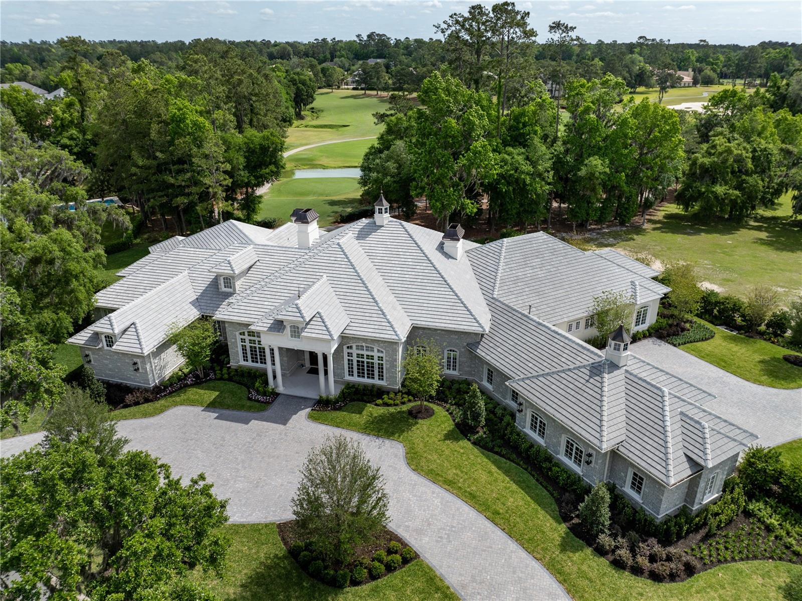 Stunning New Construction by Equestrian Luxury Homes: An Architectural Masterpiece Nestled in a coveted locale, this magnificent model home, built by Equestrian Luxury Homes and designed by the award-winning Roberts Design Group, epitomizes custom luxury and sophisticated design. With an unwavering commitment to quality, this estate features exquisite details and unmatched craftsmanship. Enter through a custom designed marble foyer, leading you through spaces enriched with Italian and lilac marble and topped with quartz, granite, and marble countertops. Floors in living areas and bedrooms are laid with hand-scraped hardwood, while hand-painted custom cabinetry and polished nickel hardware enhance the aesthetic elegance. Experience grandeur as you enter the main living area, with 16’ high ceilings, multi-layered custom crown molding, and expansive 28’ folding glass doors that seamlessly blend indoor and outdoor living. The heart of the home boasts a gourmet kitchen with double islands and state-of-the-art appliances by Sub-Zero, Wolf, and Cove. The kitchen flows effortlessly into a spacious living room, making it perfect for entertaining. A luxury equestrian room with fine walnut cabinetry complements the sophisticated theme. Specialized entertainment is provided by a state-of-the-art, Rococo-inspired theater room featuring plush seating for eight and an elegant snack bar. The private walnut library exudes classic charm with European-style millwork alongside a secluded wine cellar for the connoisseur. Bathrooms feature frameless glass shower enclosures, luxury fixtures including rain heads, and bespoke dressing rooms with leather accents, creating a spa-like atmosphere. The lanai and outdoor kitchen are crowned with walnut ceilings, providing a lavish space for al fresco dining and relaxation. The property boasts a fully hardscaped entrance and a driveway leading to a spacious four-car garage. Advanced home automation includes a full house Crestron sound and lighting system, ensuring every element is controlled at your fingertips. This home is a true sanctuary, offering a blend of luxury, comfort, and technology, ideal for the discerning homeowner looking for an extraordinary living experience. Welcome to a life of luxury and elegance in this architectural gem.