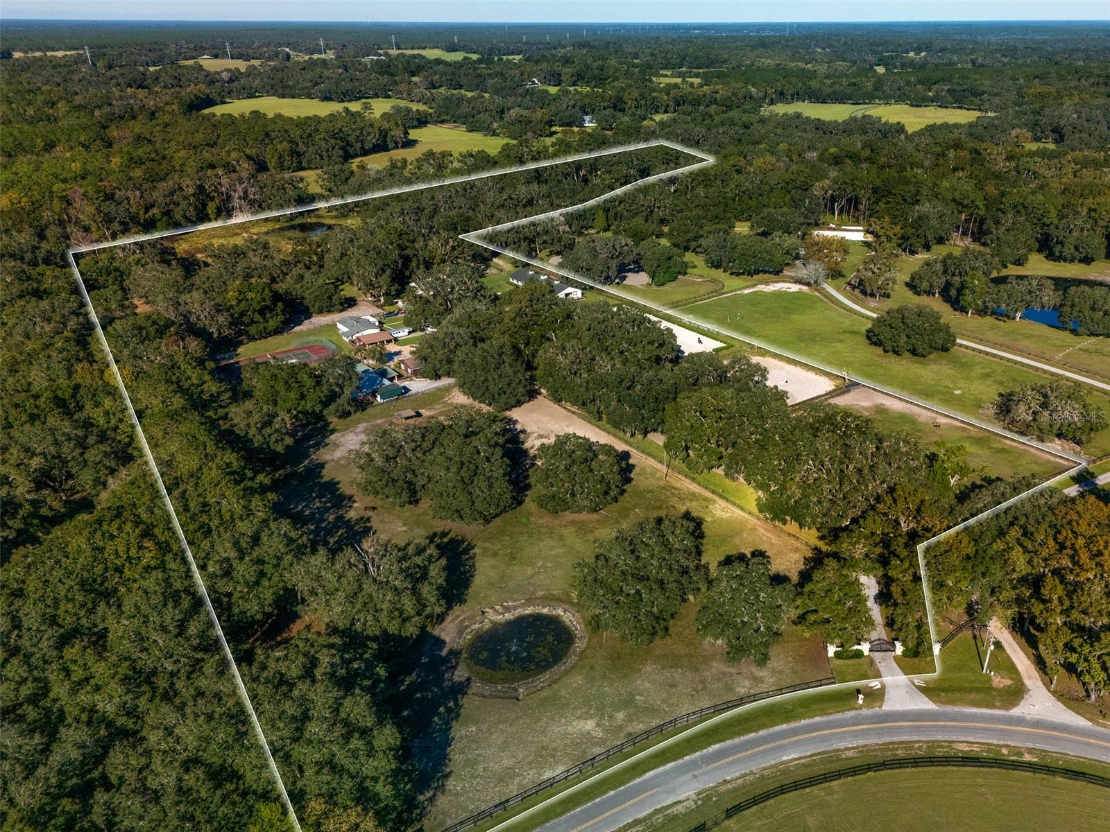 This 19+ acre fully fenced farm offers multiple living areas and the perfect setup for horses and riders, located less than 20 minutes from the World Equestrian Center. Majestic oak trees frame the landscape, creating a peaceful setting throughout the property. The main two-story residence features 3 bedrooms and 3 bathrooms, with the primary suite conveniently located on the main floor. A second home, a 3-bedroom, 2-bathroom mobile home, provides additional living space for guests, staff, or extended family. Adjacent to the second home are two additional rental units, a cozy studio with a bathroom and a comfortable 1 bedroom, 1 bathroom apartment, offering excellent options for income potential or on-site accommodations. Outdoor amenities abound, including an inviting inground pool and a private tennis court. The property is designed for serious equestrians, featuring two well-equipped barns, both with CEM-approved stalls and hot-water wash racks. The first barn includes 15 stalls, a tack room, and a feed room, while the second offers 8 stalls, a tack room, a bathroom, and an additional wash rack. Training facilities include a professionally constructed arena by Gentry Bulldozing, featuring a premium sand, fiber, and cloth footing mixture, along with a round pen. This property offers an outstanding opportunity for horse enthusiasts seeking a well-equipped and versatile farm.
